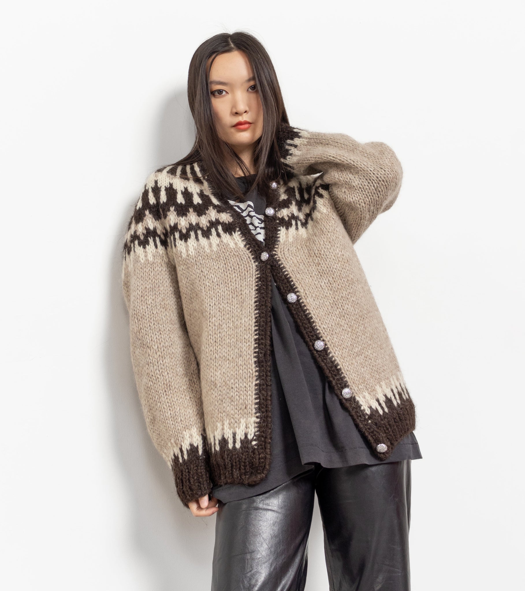 A woman wearing a beige and brown fuzzy wool cardigan with a crew neck and metallic buttons, paired with black pants.