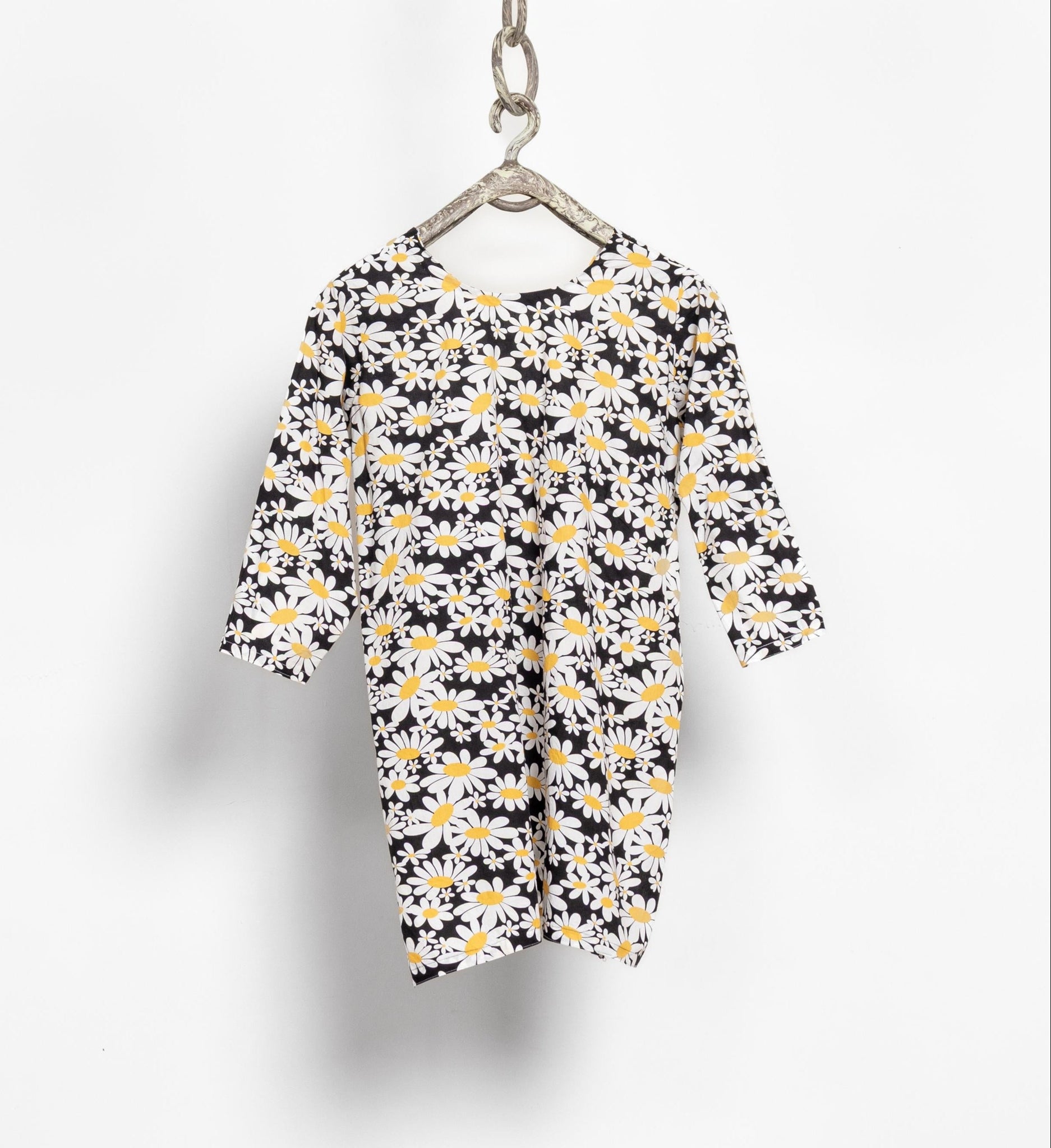 Floral dress with black background on a hanger against a white background