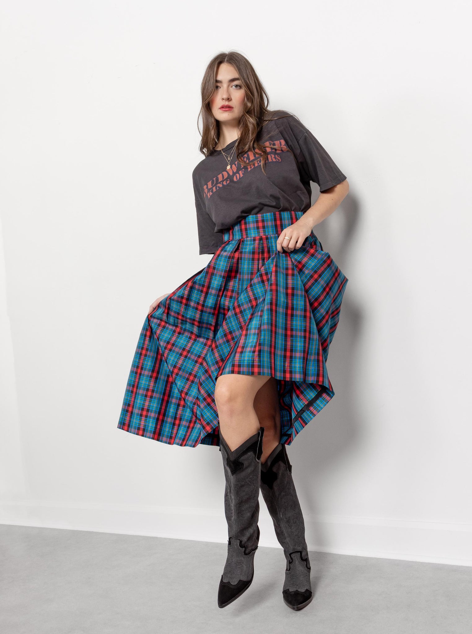 Woman wearing a plaid skirt and gray t-shirt against a white background