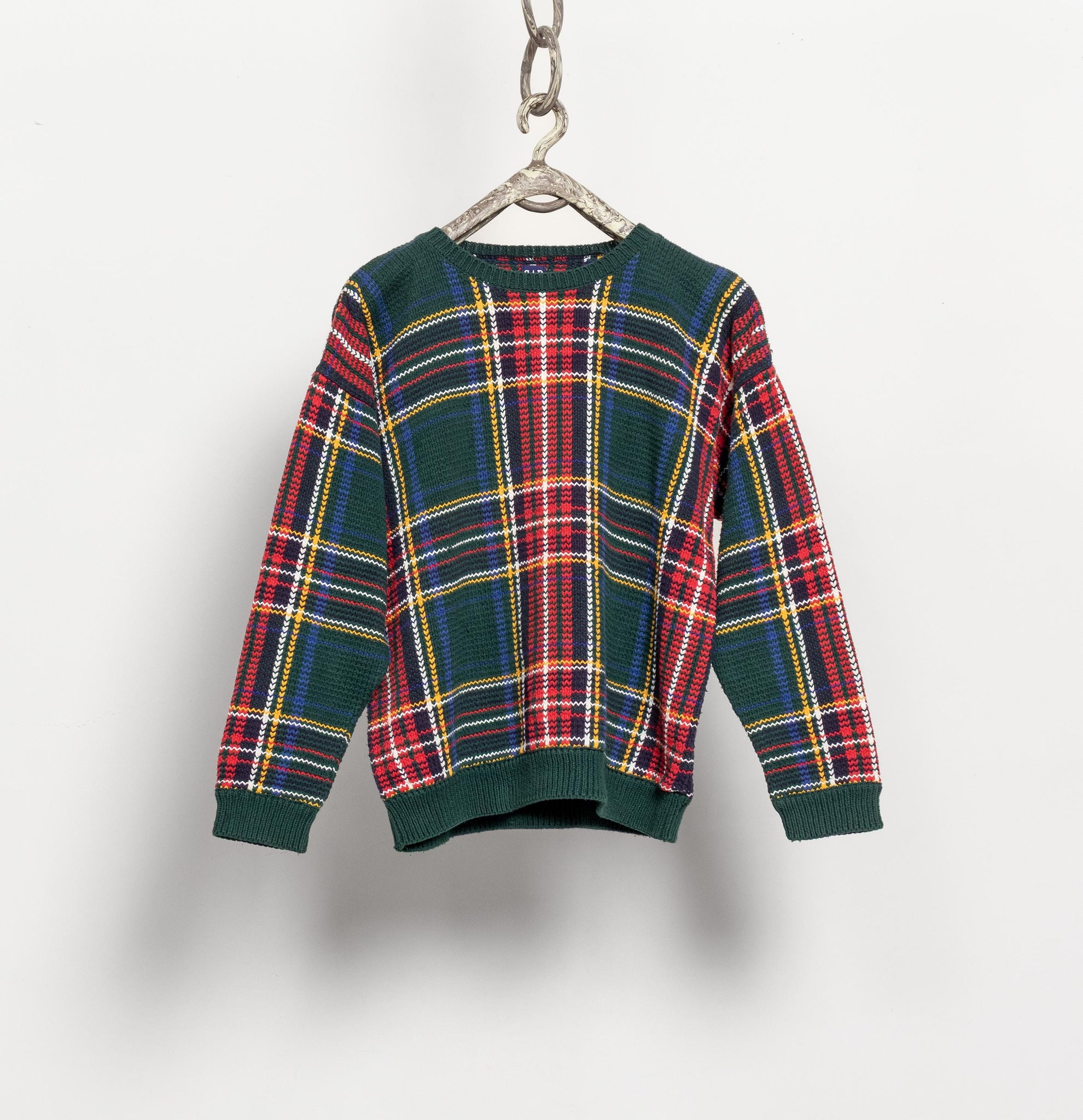 Plaid sweater on a hanger against a white background