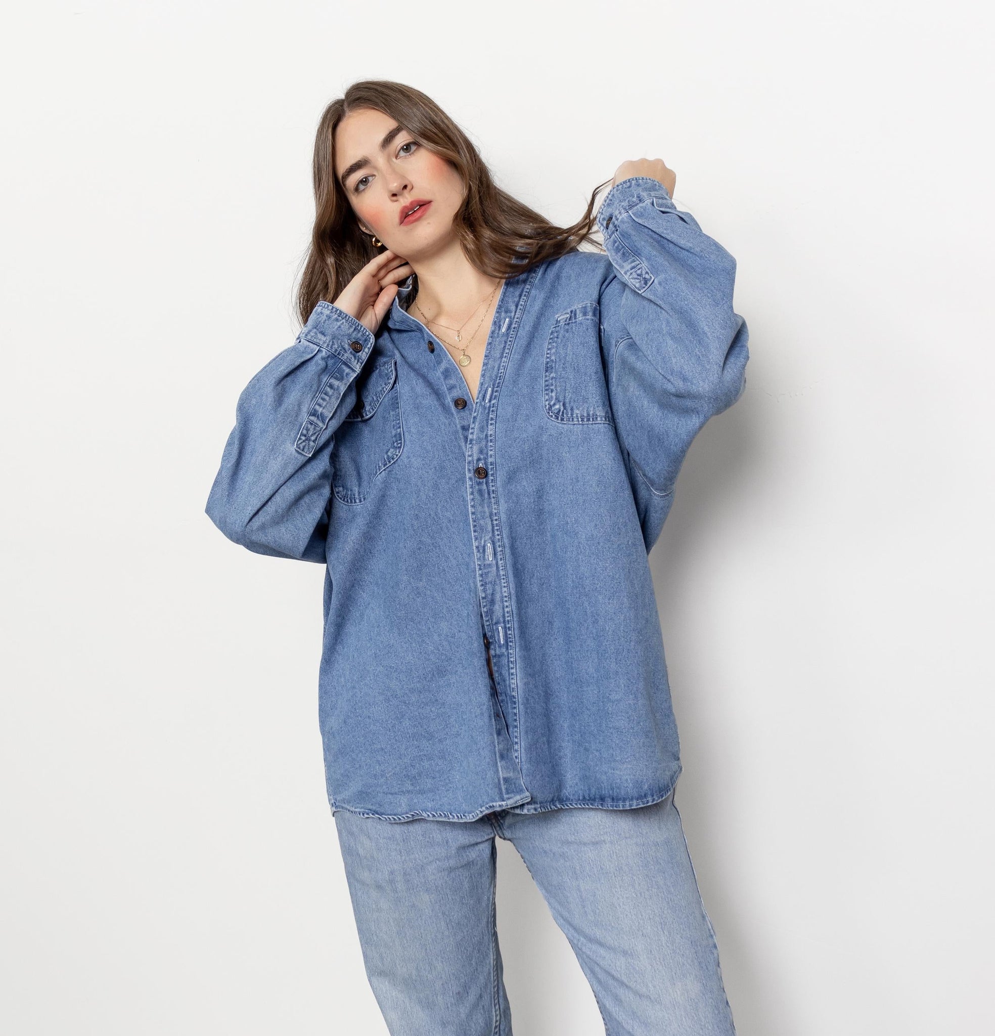 Woman wearing a blue denim shirt and jeans on a white background