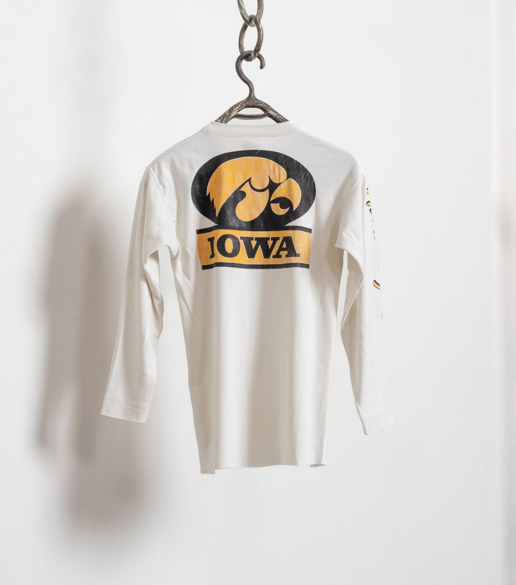 Vintage long sleeve white Iowa Hawkeyes t-shirt with a graphic on the front, hanging against a plain background.