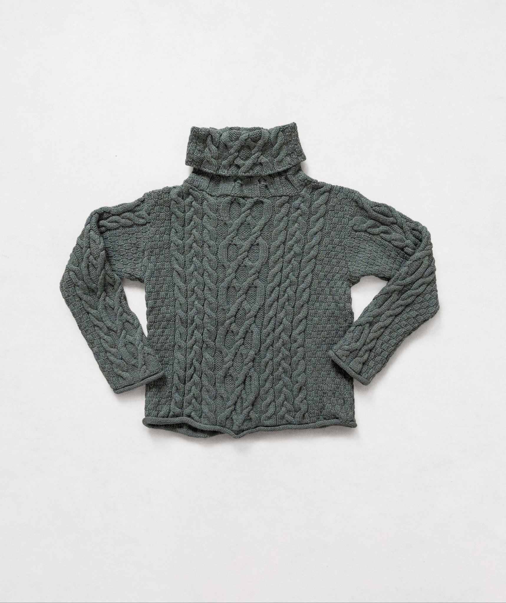 Green cable knit sweater on a white background