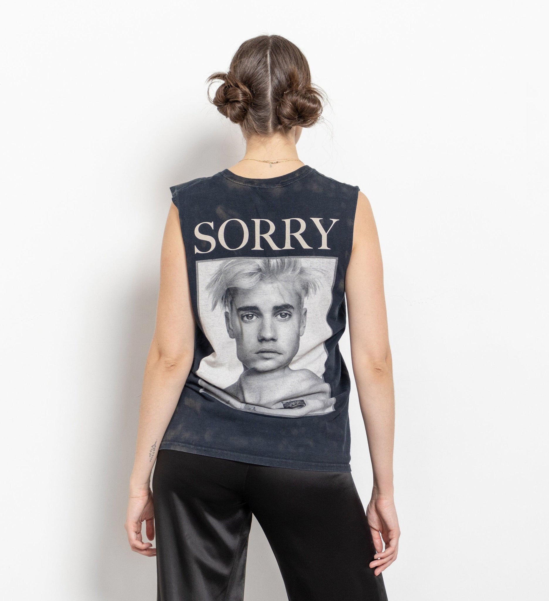 A person wearing a sleeveless black t-shirt with a graphic of Justin Bieber and the word 'SORRY' printed above the image.
