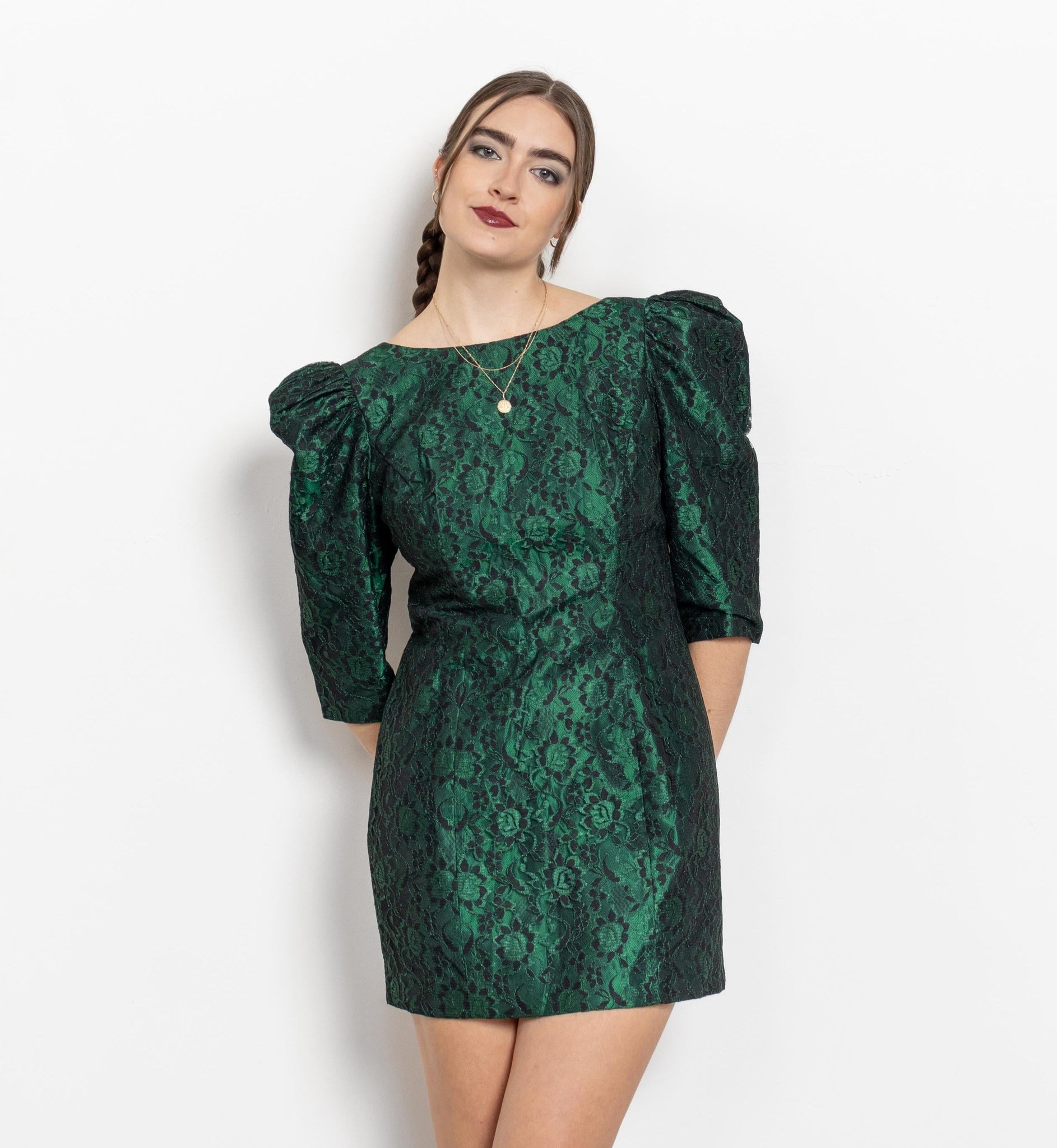A woman wearing a vintage green lace mini dress with puff sleeves, knee-length, solid color, with a patterned design.