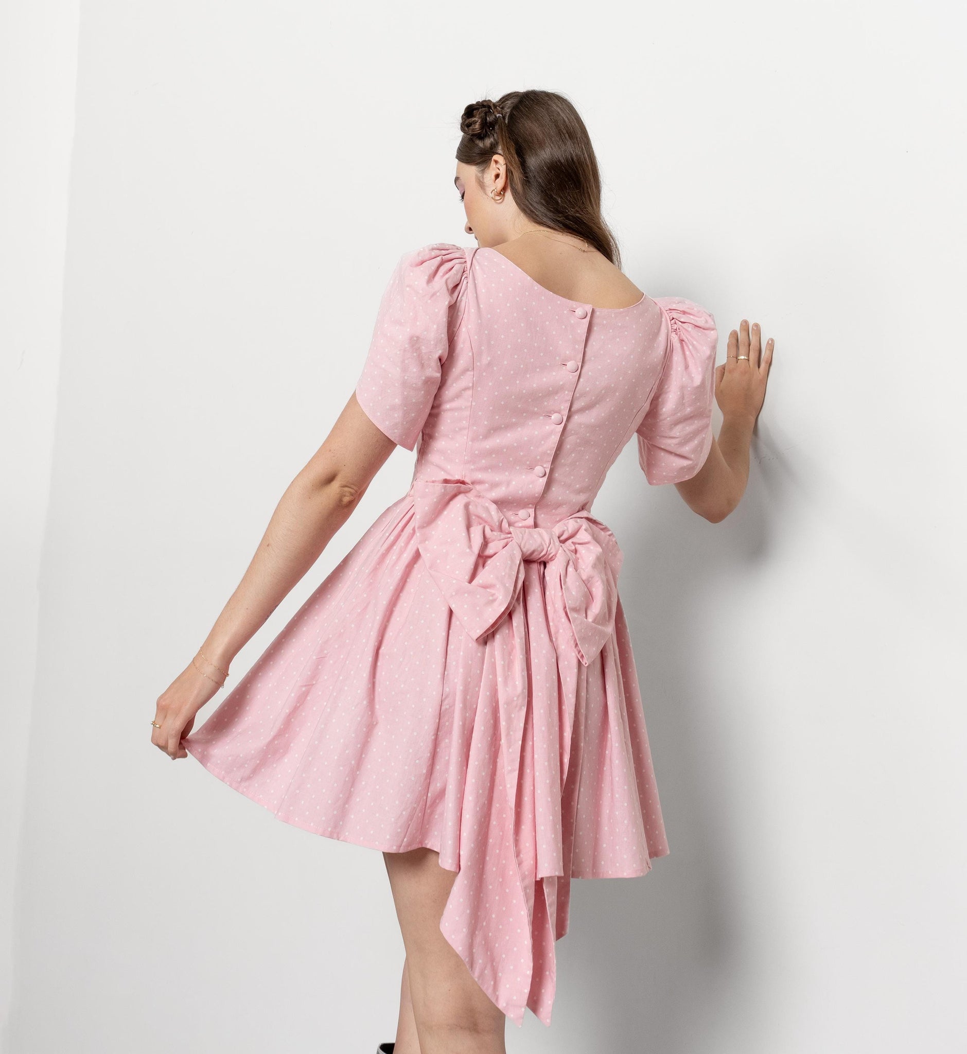 Woman wearing a pink dress with puff sleeves against a white background