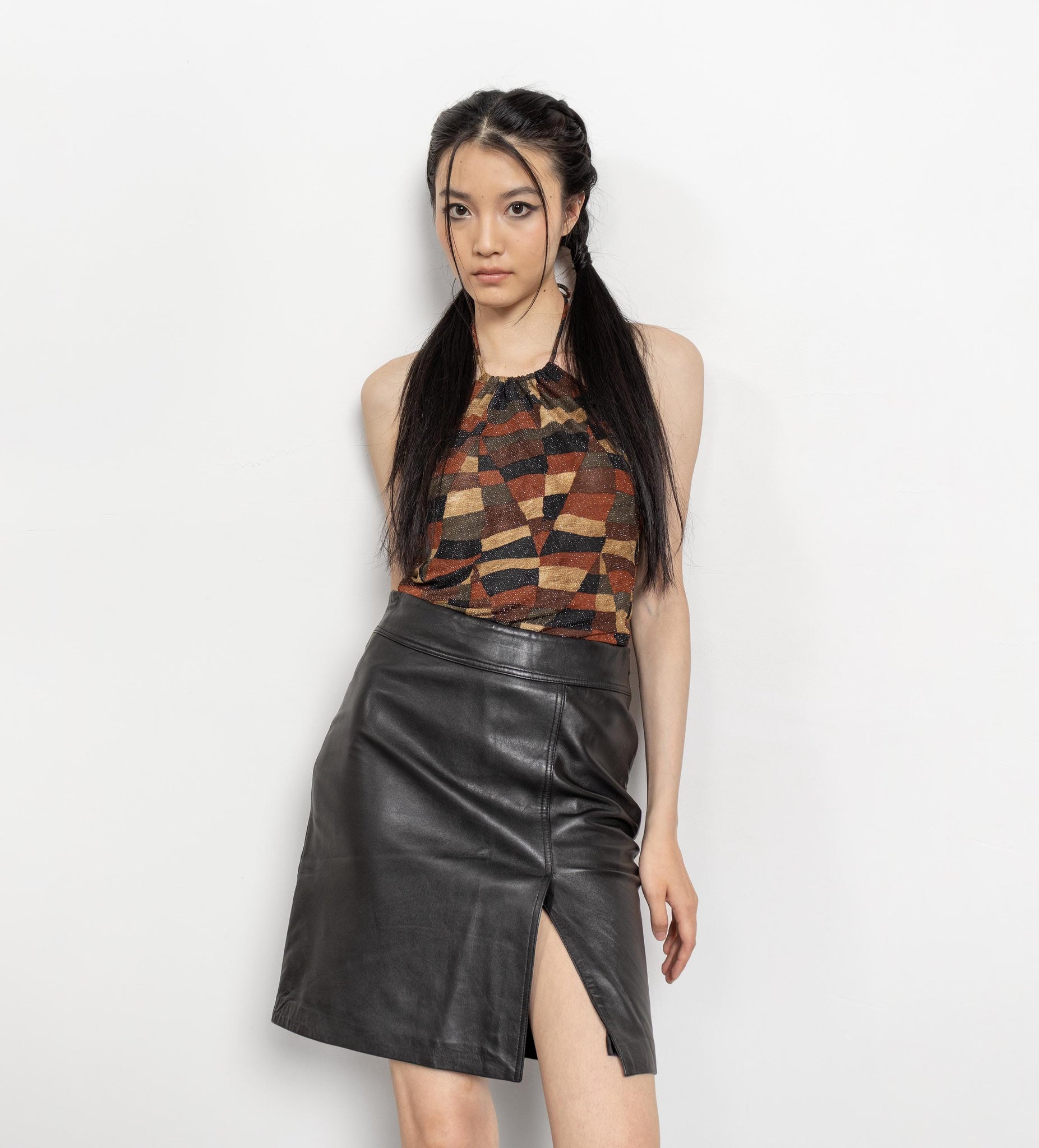 Woman wearing a patterned top and black leather skirt on a white background
