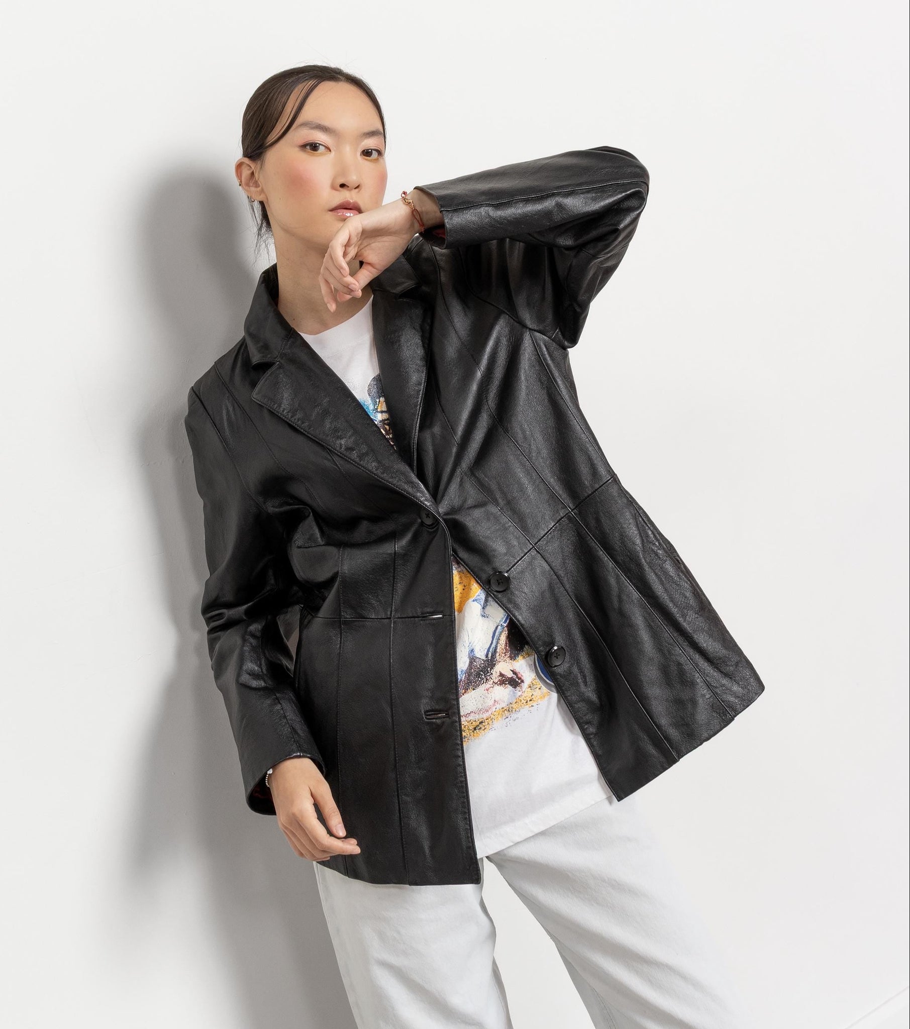 Person wearing a black jacket over a white outfit on a plain background