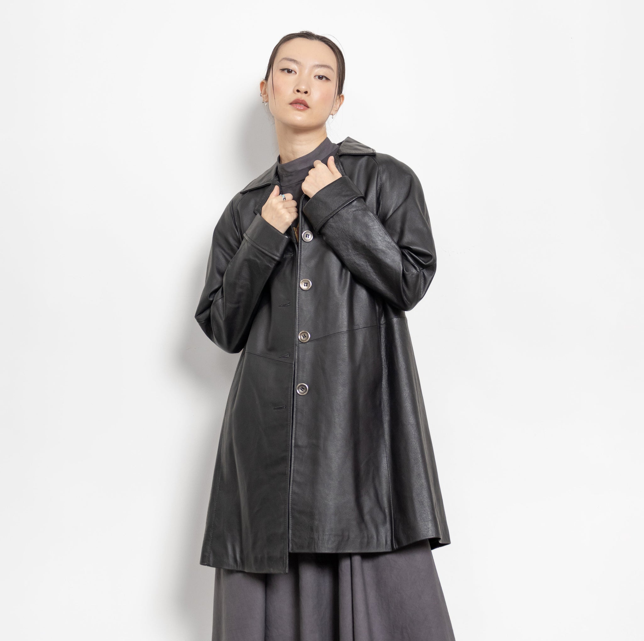 Person wearing a dark gray coat and skirt set on a white background