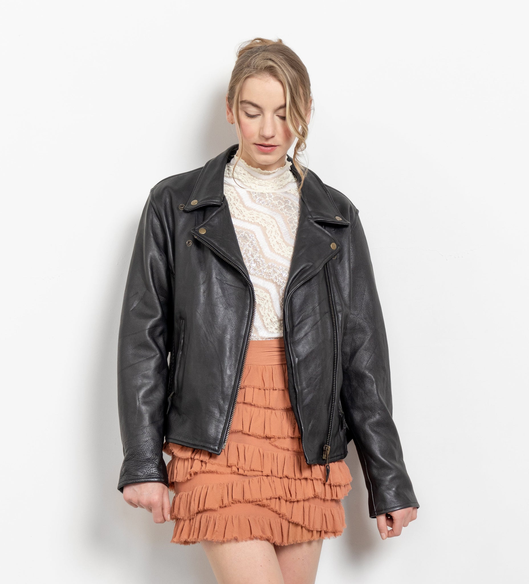 Woman wearing a black leather jacket, white sweater, and orange skirt on a white background