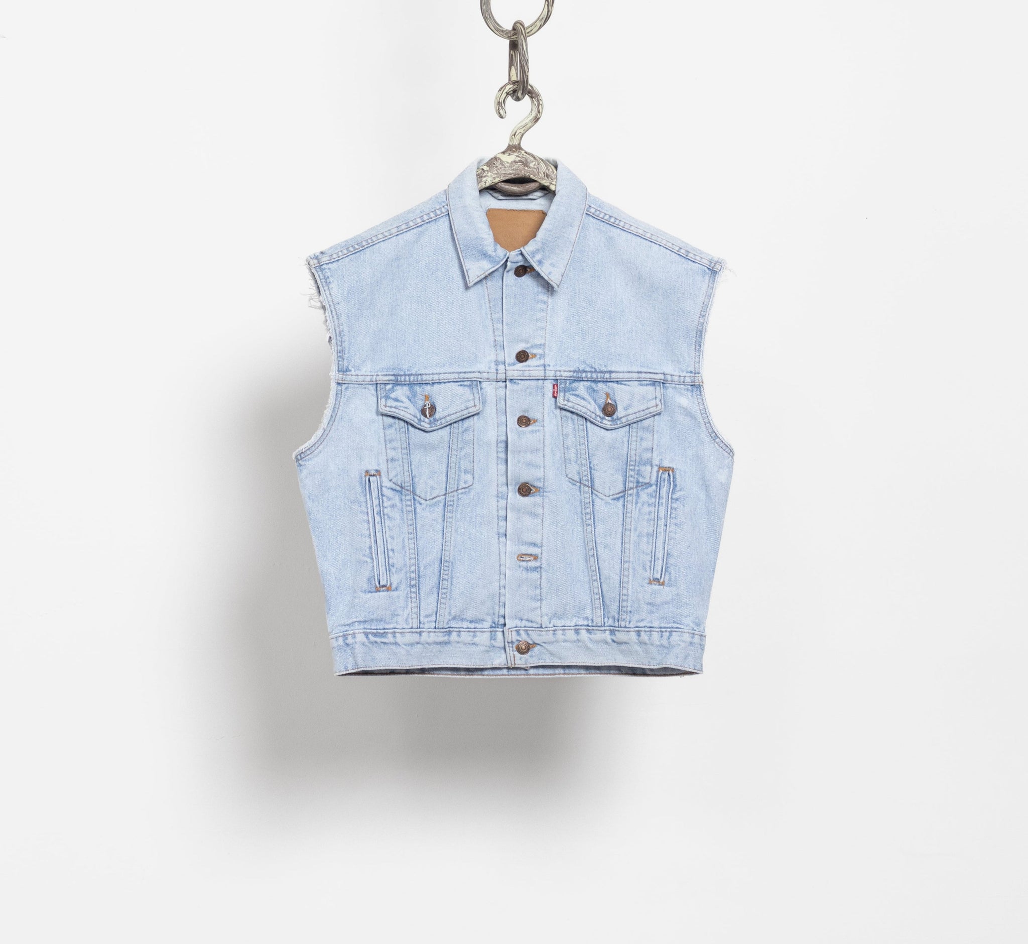 Denim vest hanging on a white background