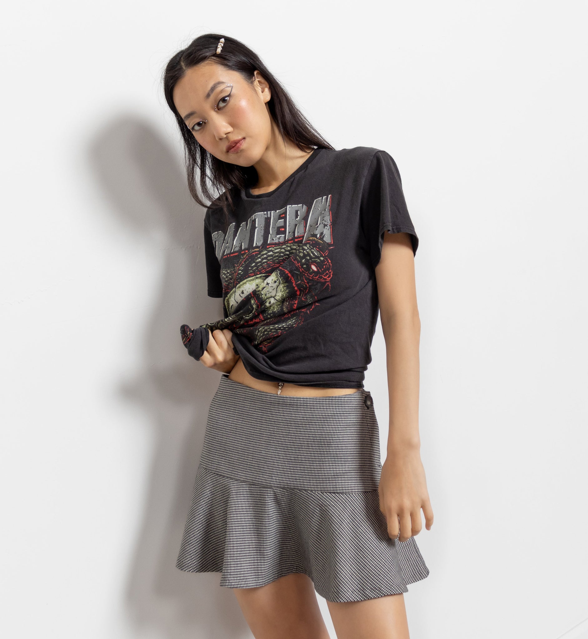 Woman wearing a black graphic t-shirt and gray skirt on a white background