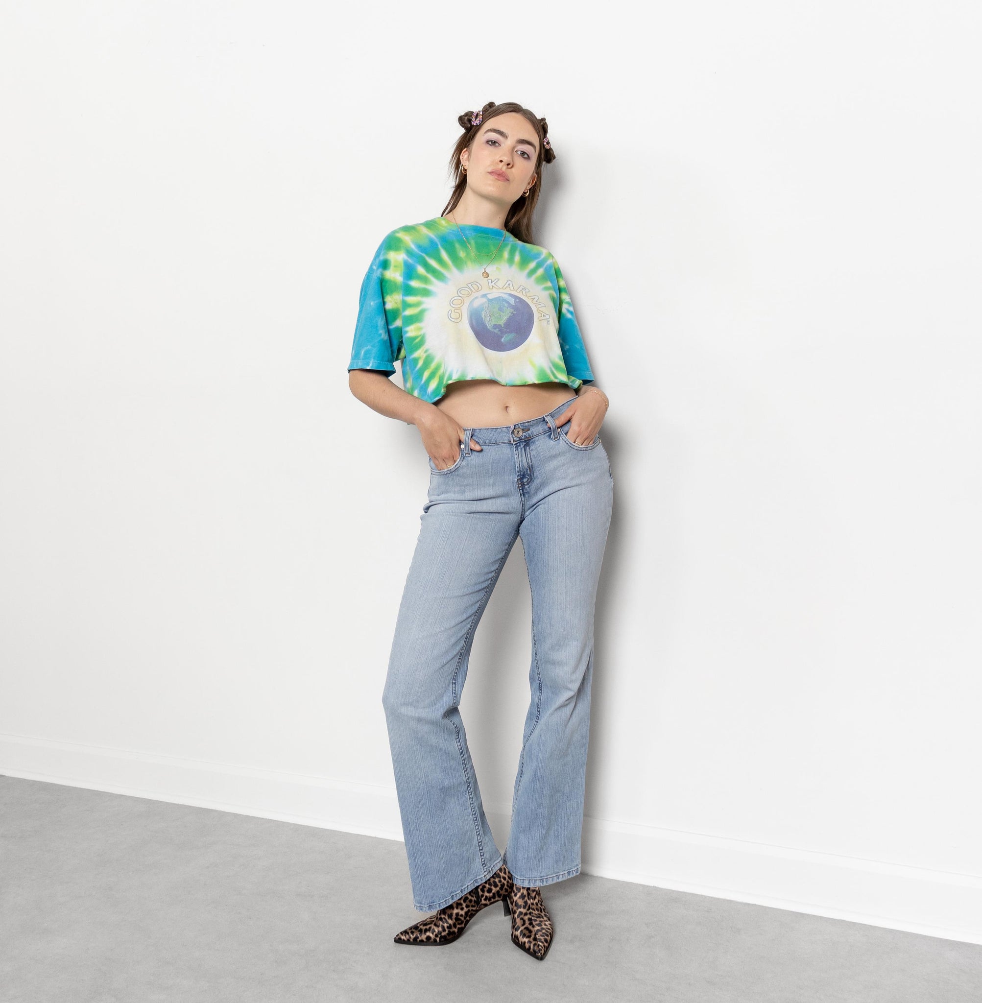 Person wearing a tie-dye crop top and light blue jeans against a white background