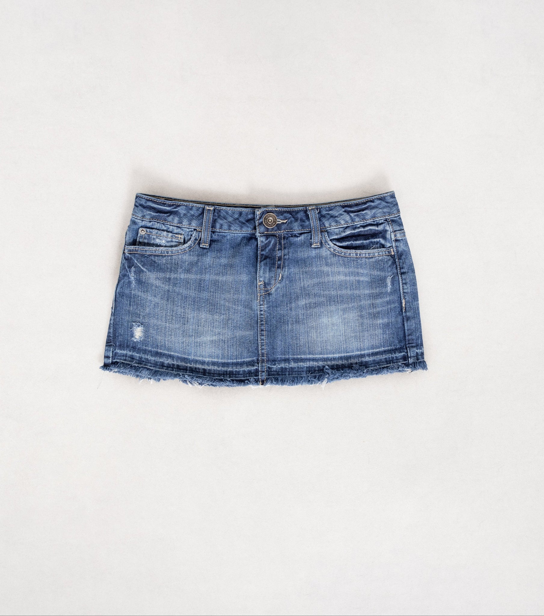 A vintage 2000's ultra low rise denim mini skirt with distressing and fading, featuring yellow stitching.