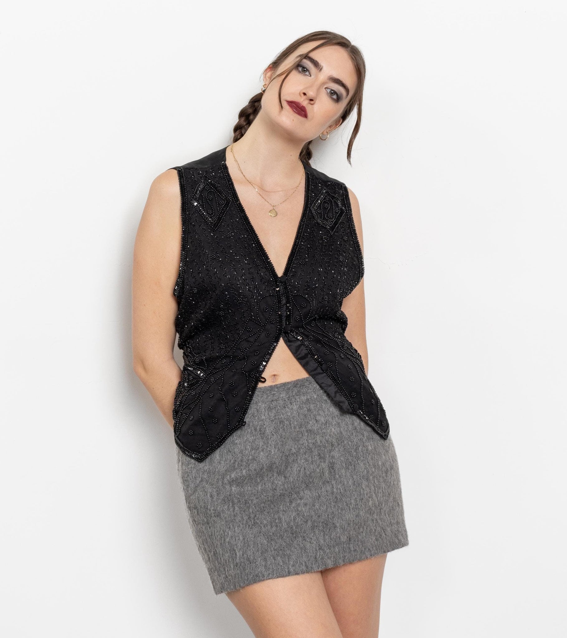Woman wearing a black sleeveless top and gray skirt on a white background