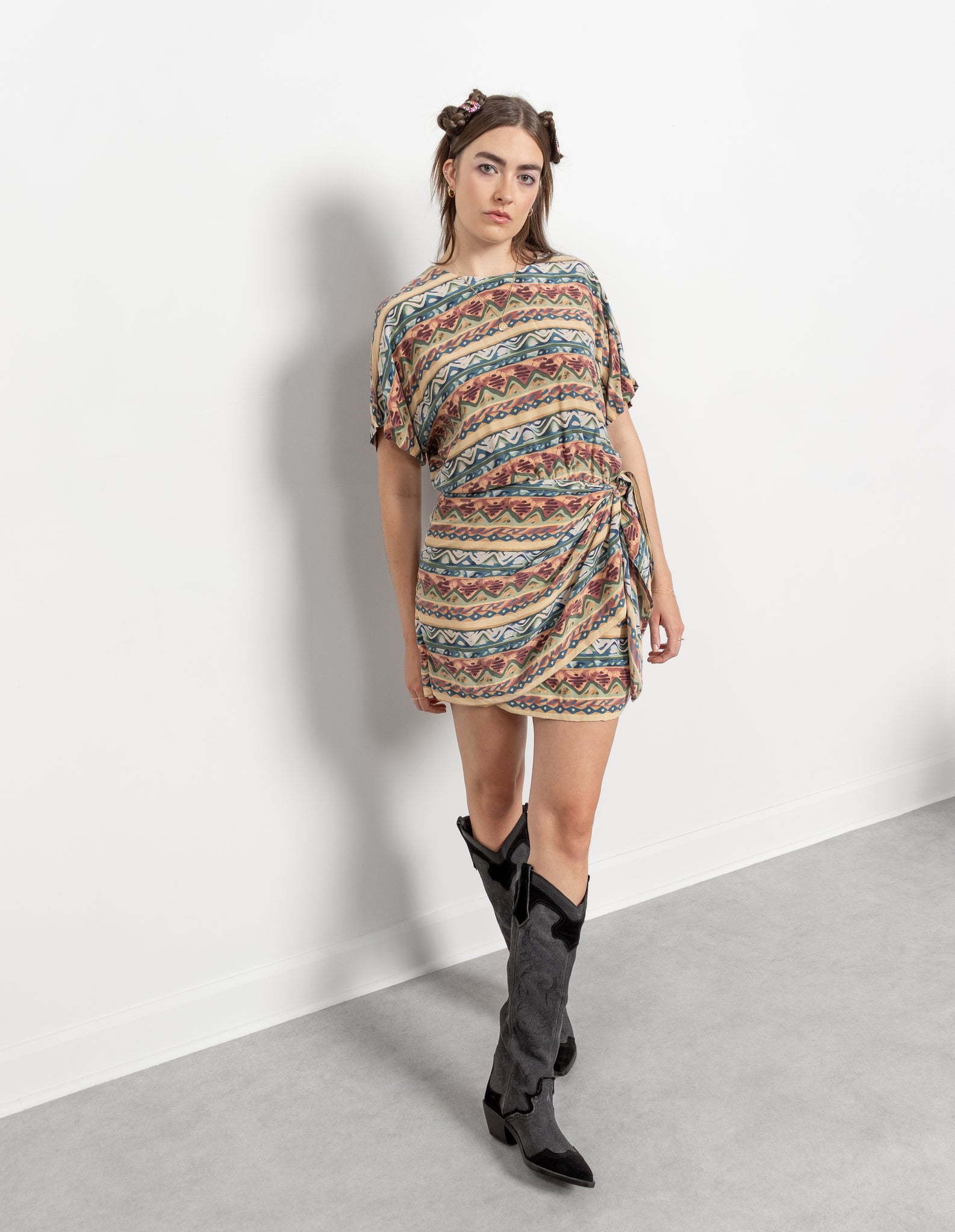 Woman wearing a patterned dress and black boots on a white background