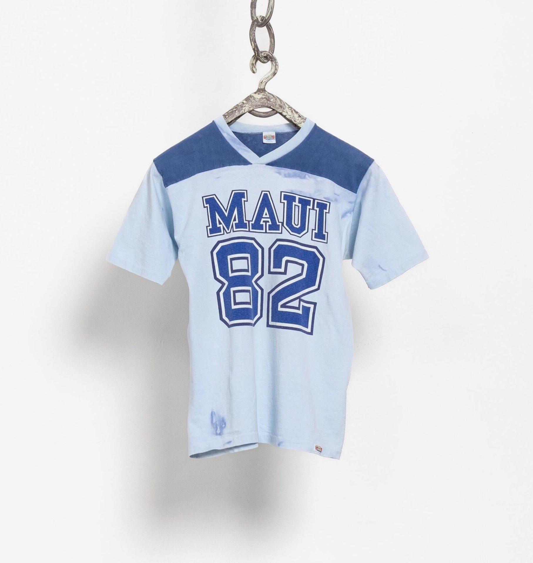 A blue and white vintage sports jersey with the number 82 and the text 'MAUI' on it, displayed on a hanger against a white background.