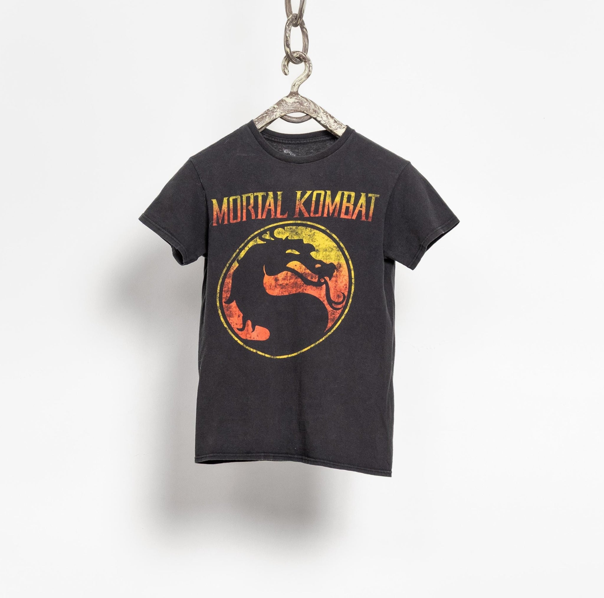 Black t-shirt with 'Mortal Kombat' logo on a hanger against a white background