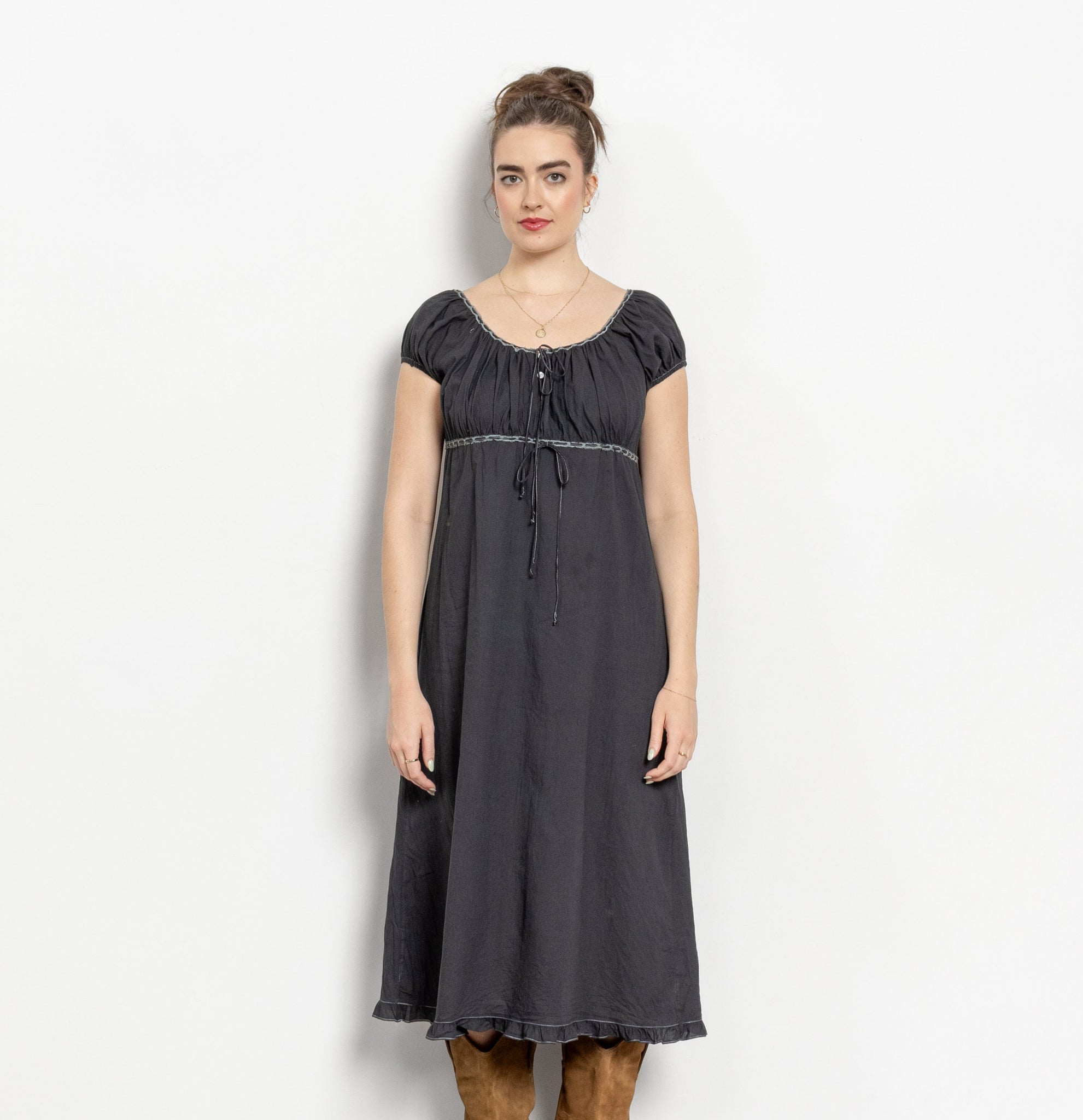 Woman wearing a dark gray dress with brown boots on a white background