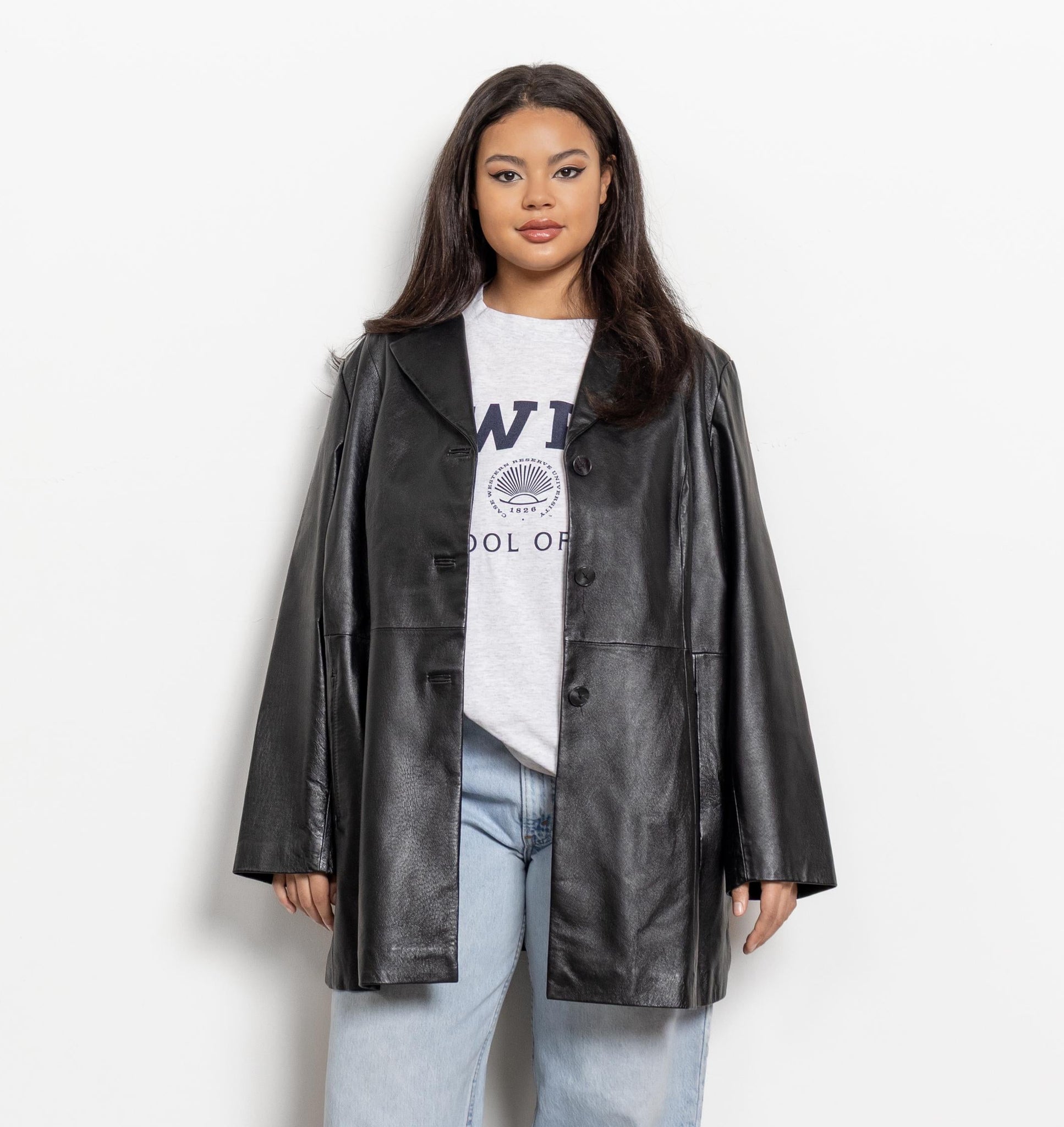 Person wearing a black leather coat over a white graphic t-shirt on a white background