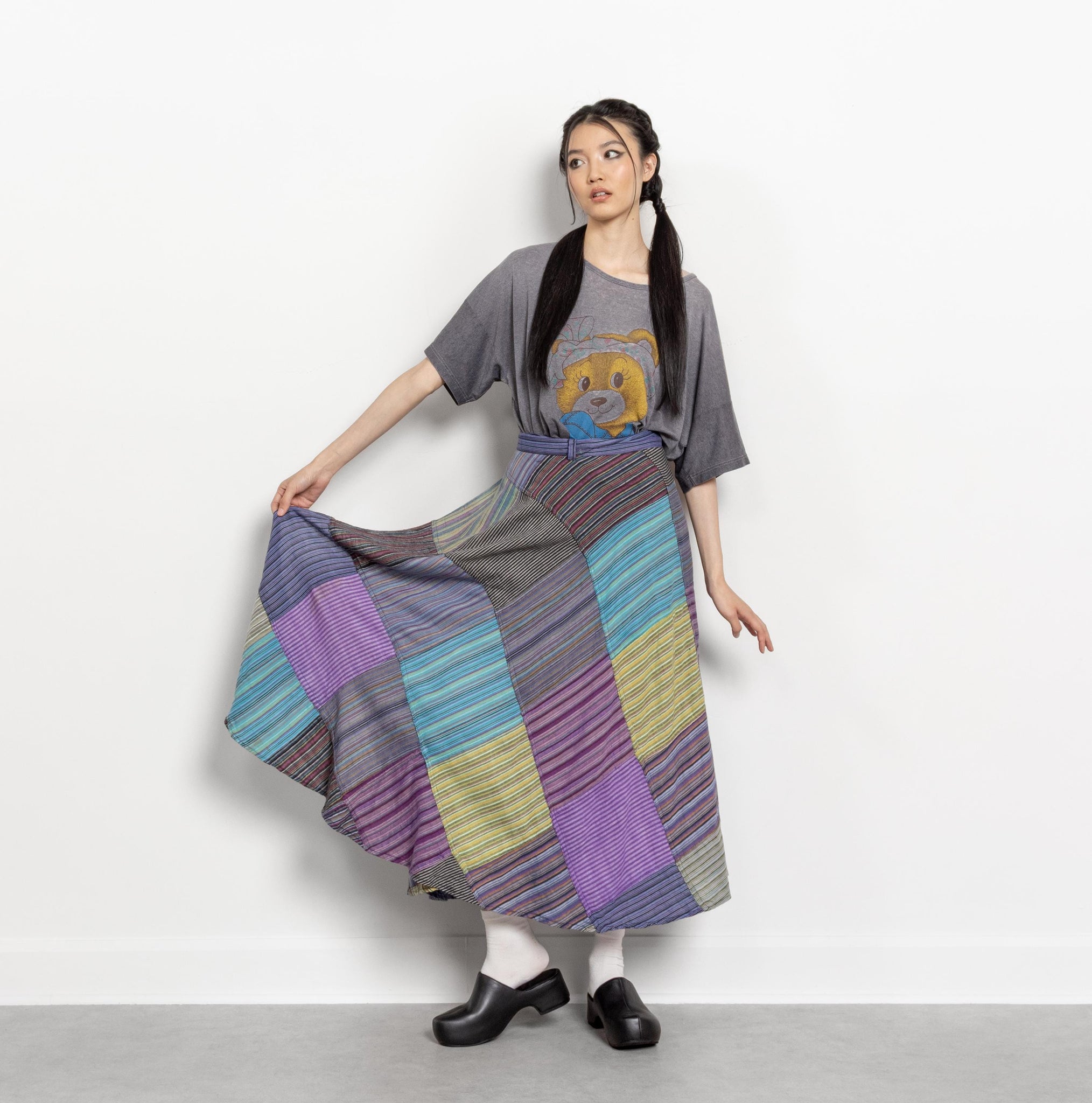 Woman wearing a colorful patchwork skirt and gray t-shirt with a lion graphic.