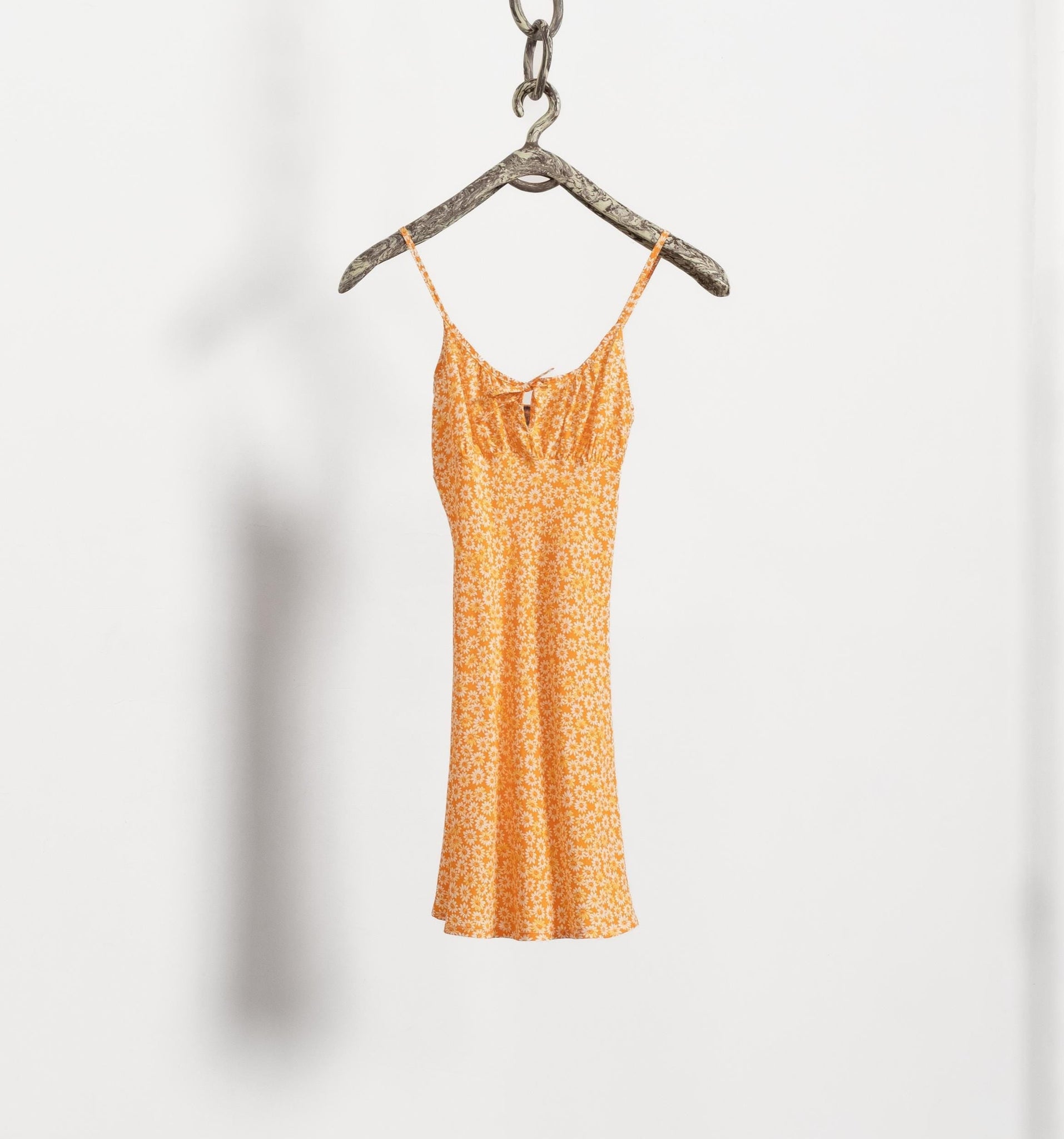 Orange floral dress on a hanger against a white background