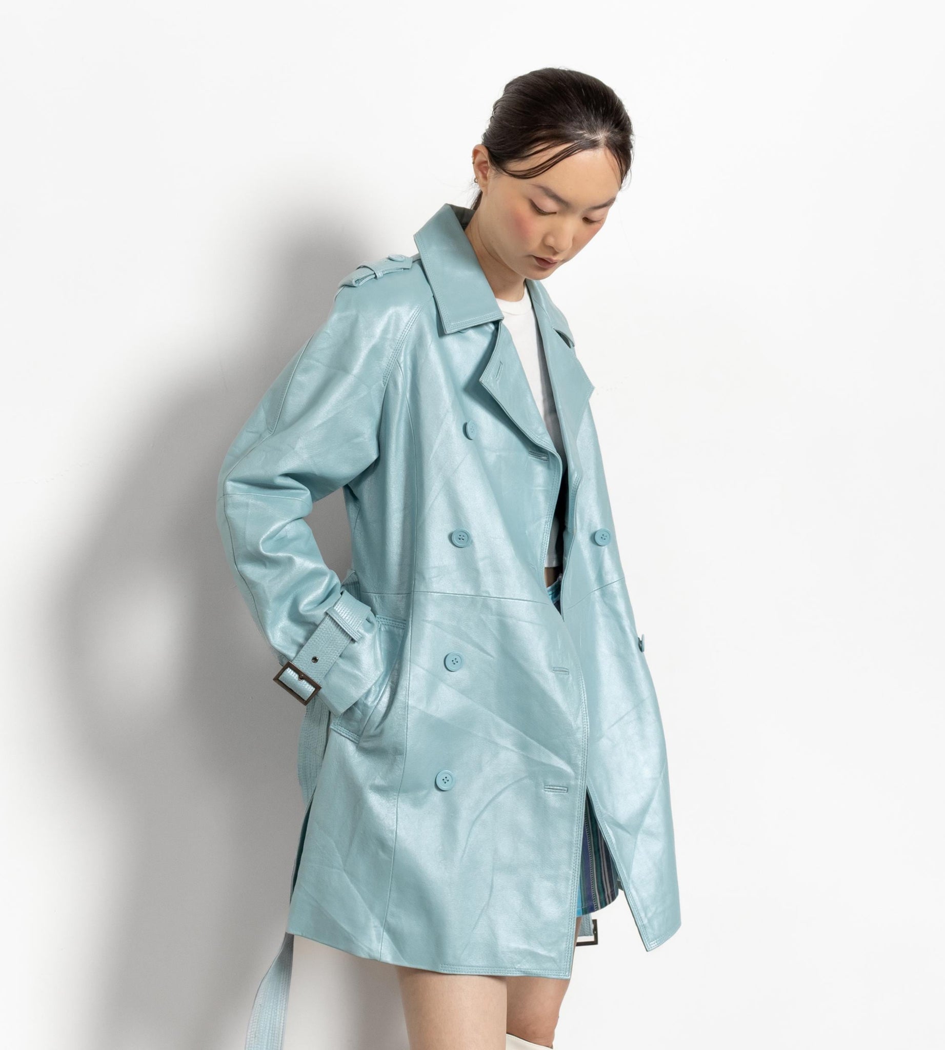 Person wearing a light blue trench coat on a white background