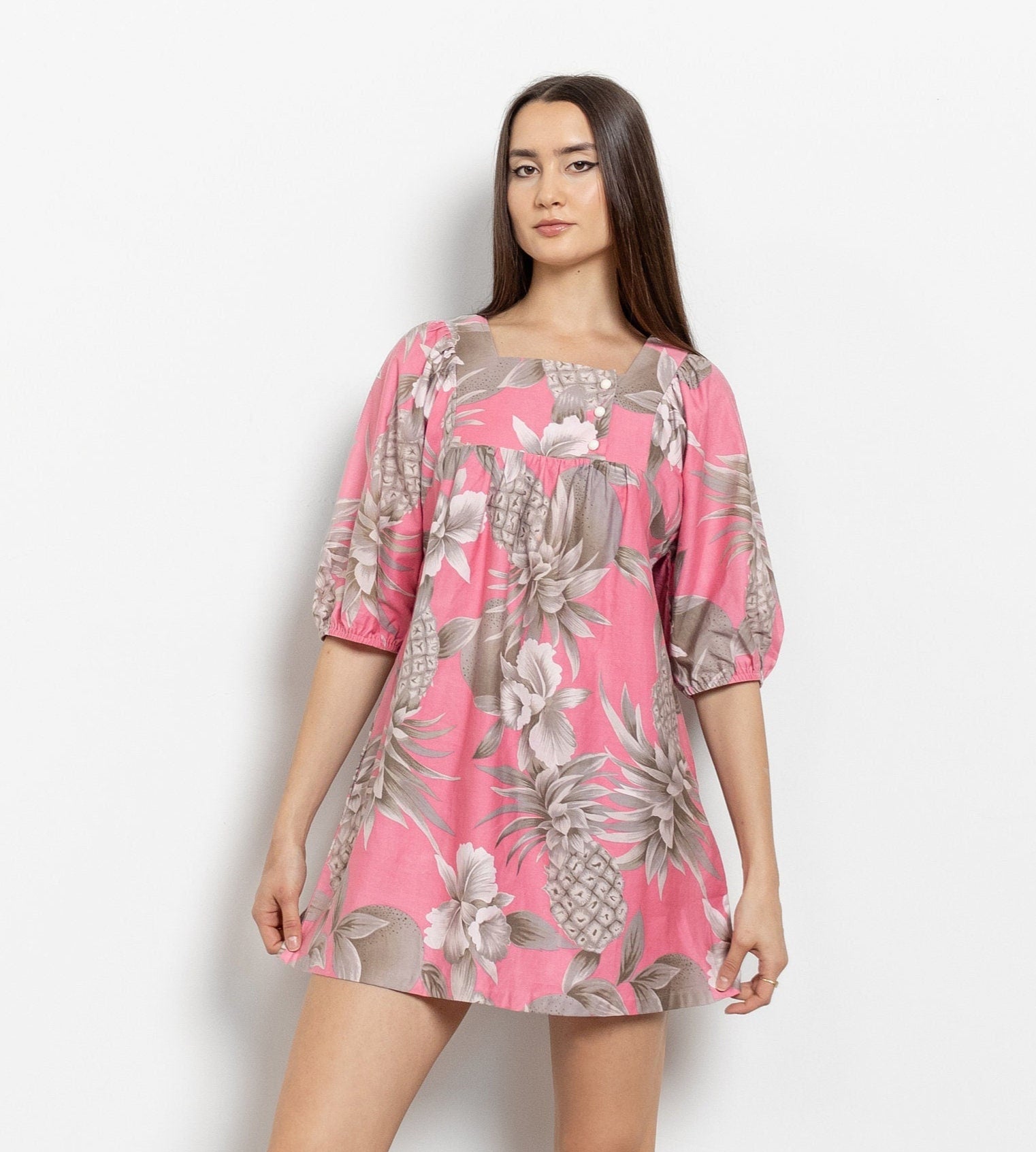 A model wearing a vintage pink floral muumuu dress with a grunge aesthetic.