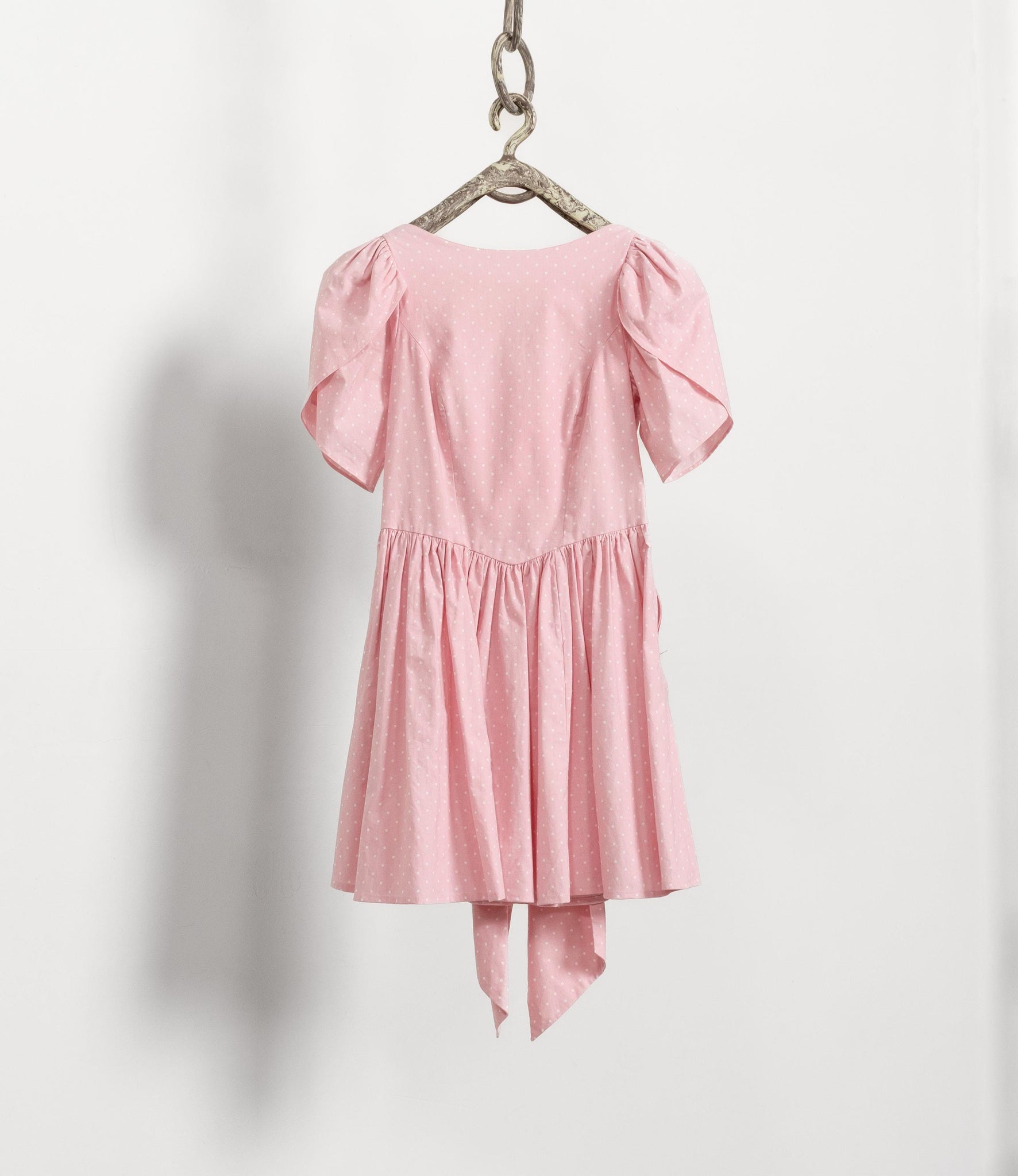 Pink dress with puff sleeves hanging on a white background