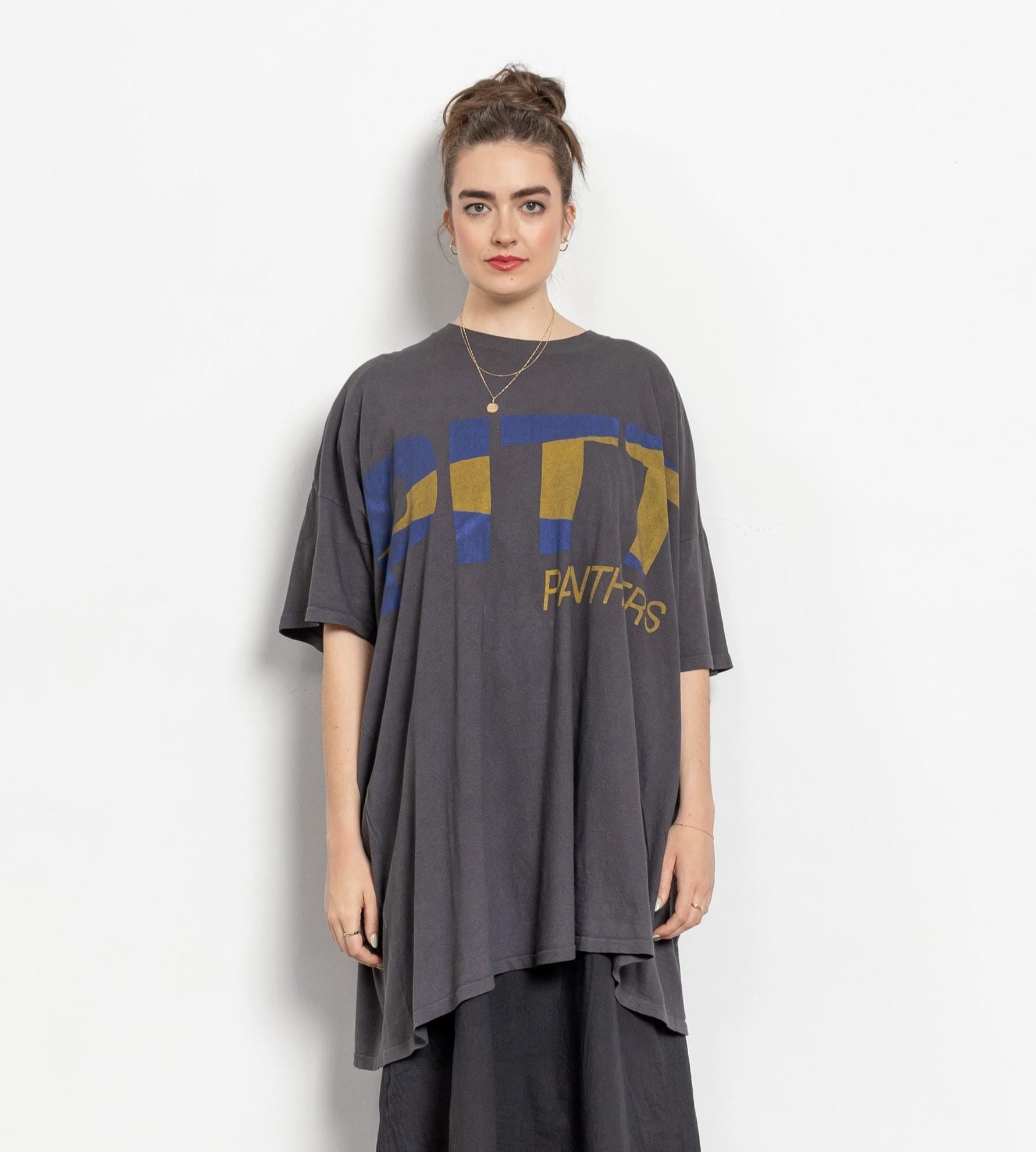 Woman wearing a gray oversized t-shirt with blue and yellow graphics on a white background