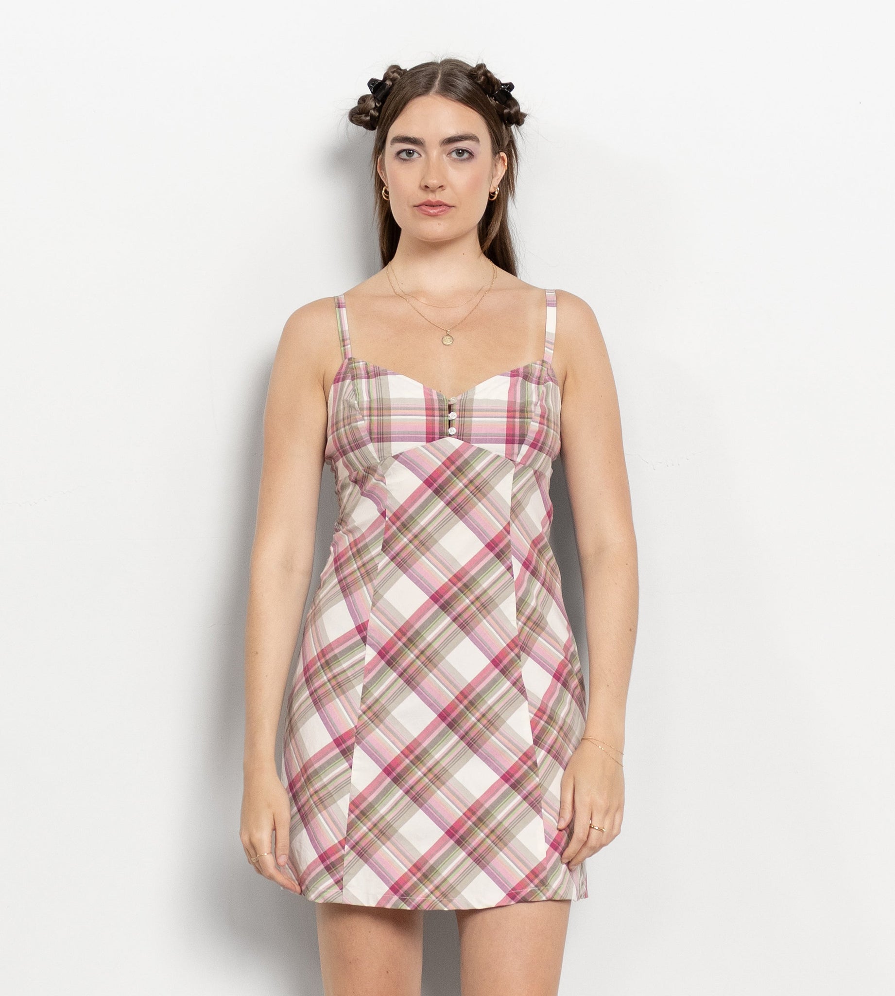 Woman wearing a plaid dress with white boots on a plain background