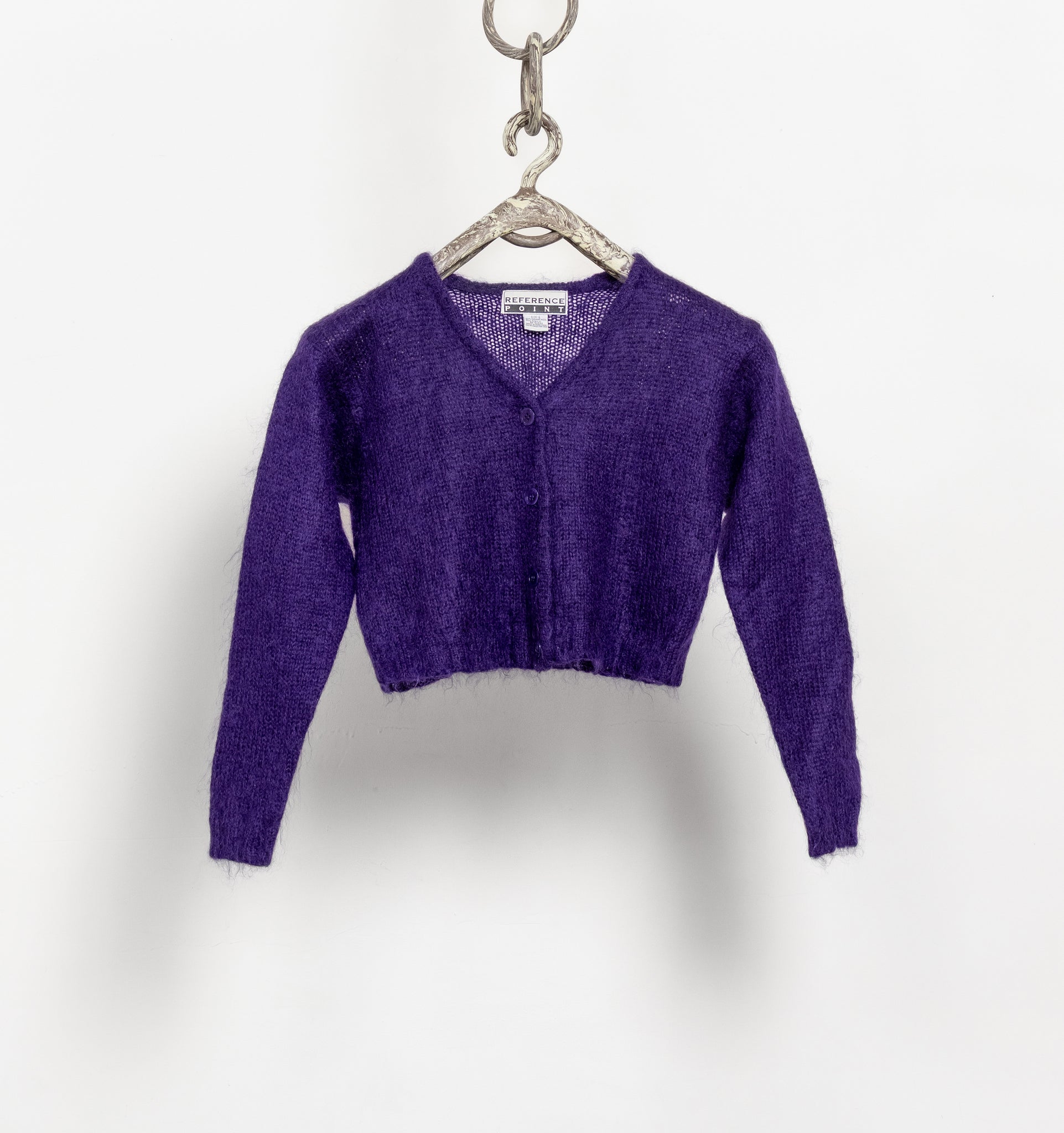 Purple sweater on a hanger against a white background