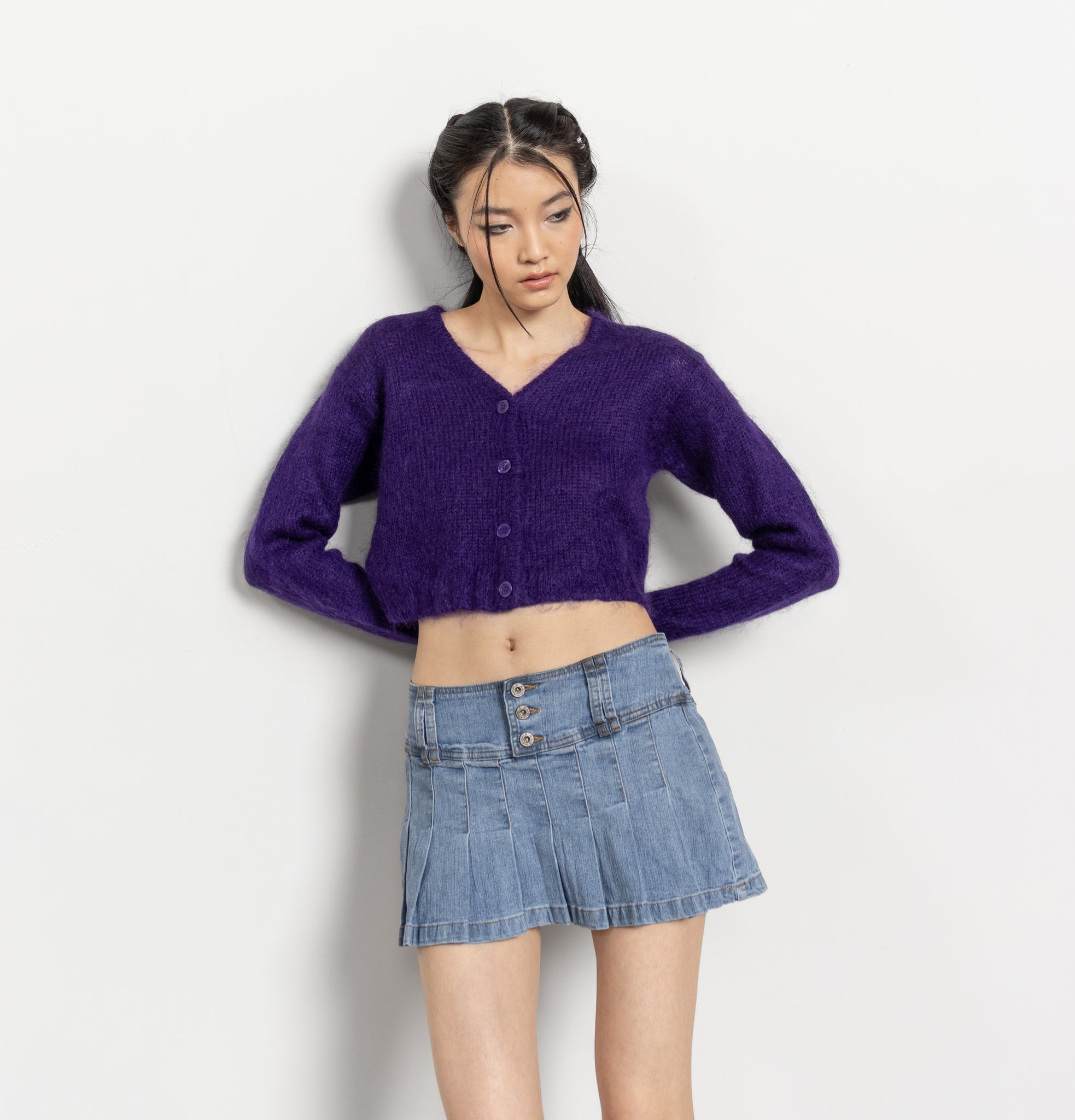 Woman wearing a purple sweater and denim skirt on a white background