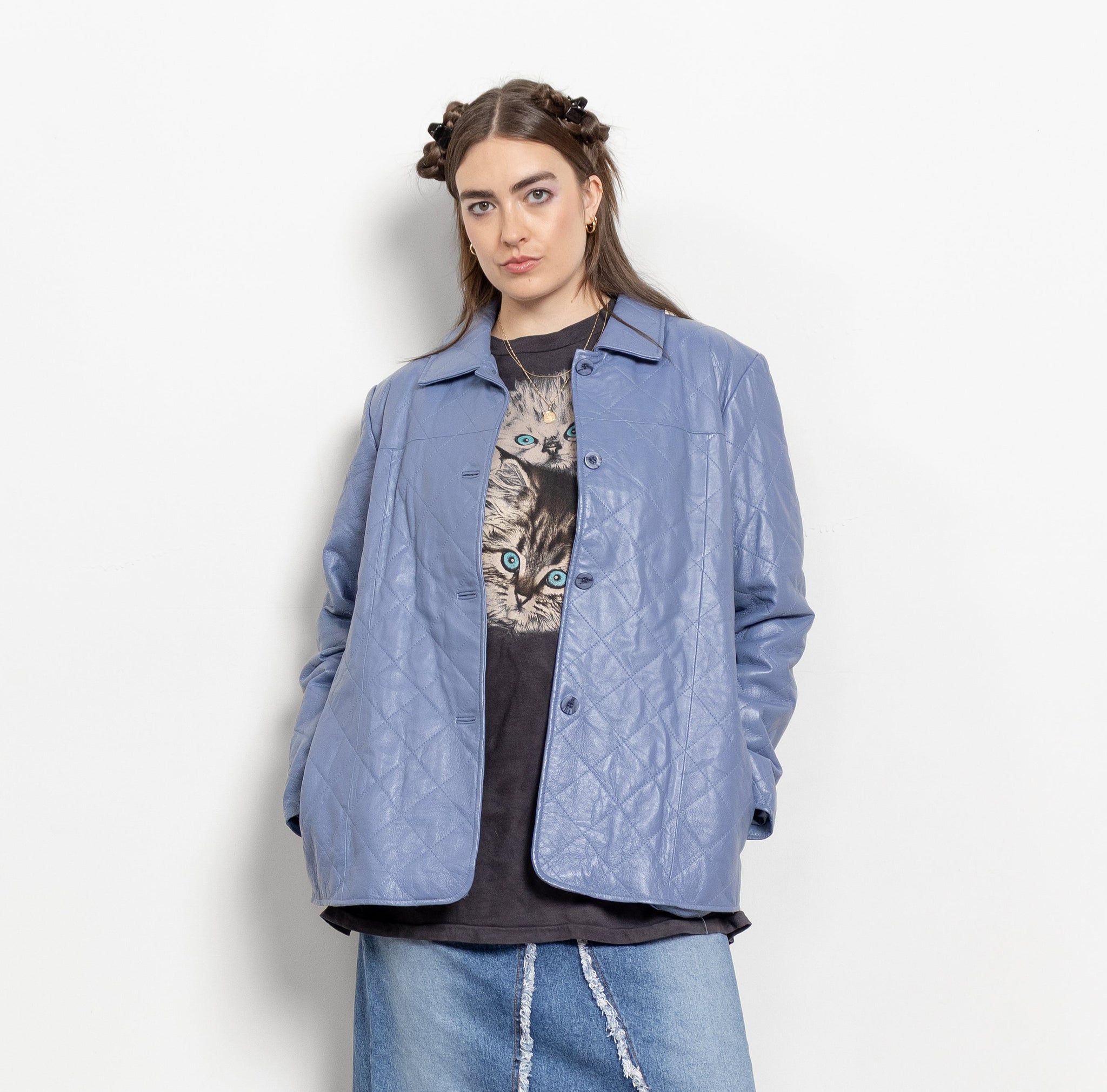 Person wearing a blue denim jacket and skirt with a white background