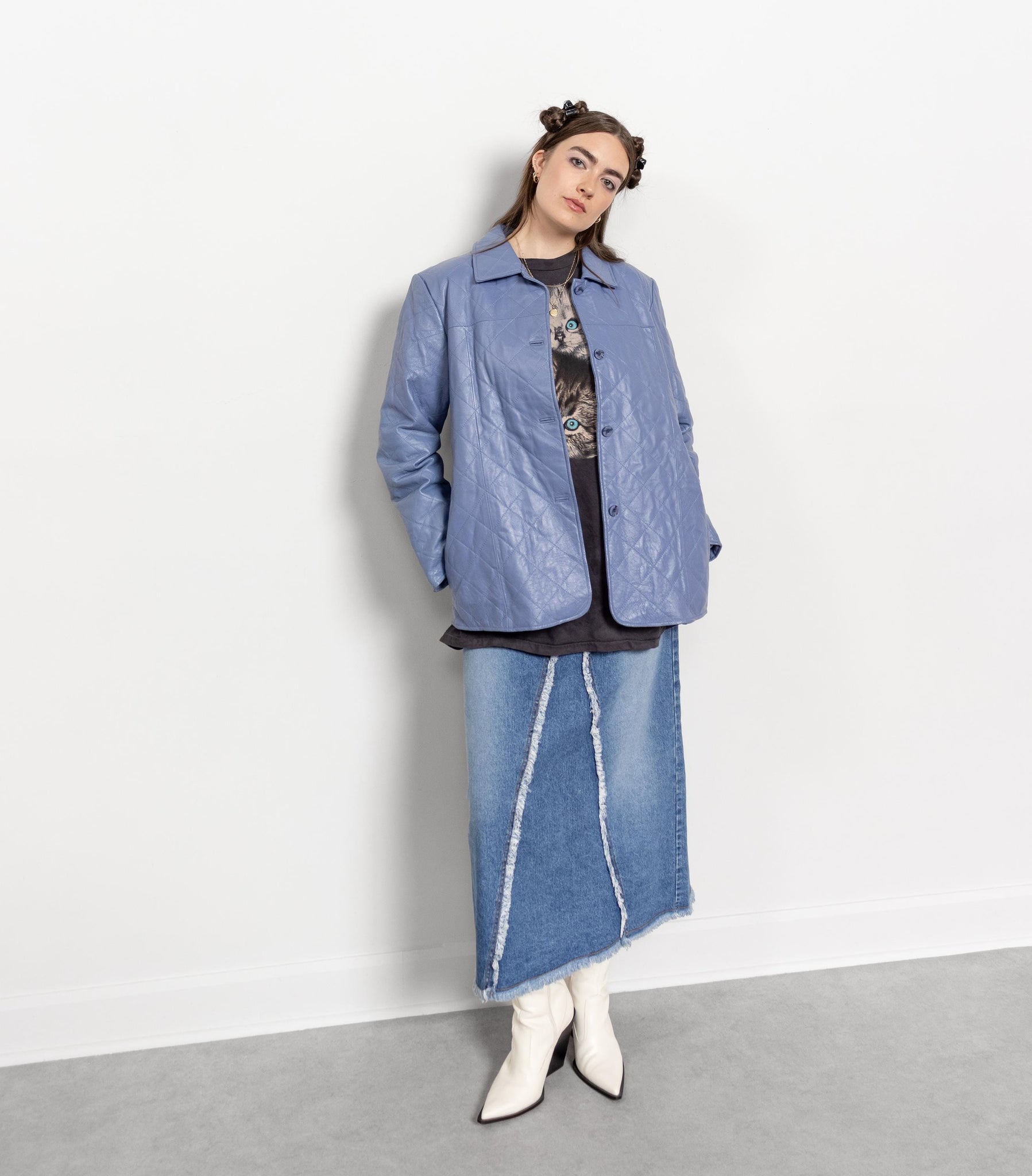 Person wearing a blue jacket and denim skirt against a white background