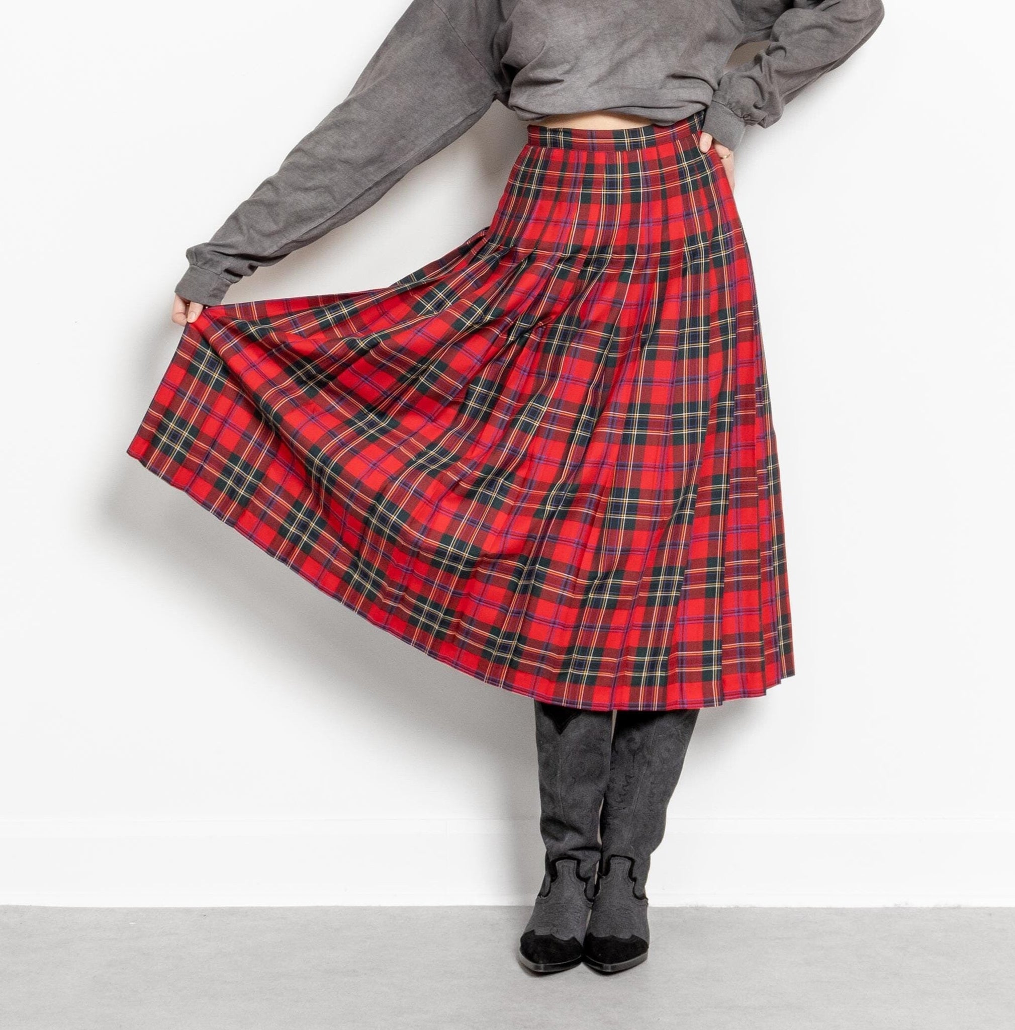 Person wearing a red plaid skirt with a plain background