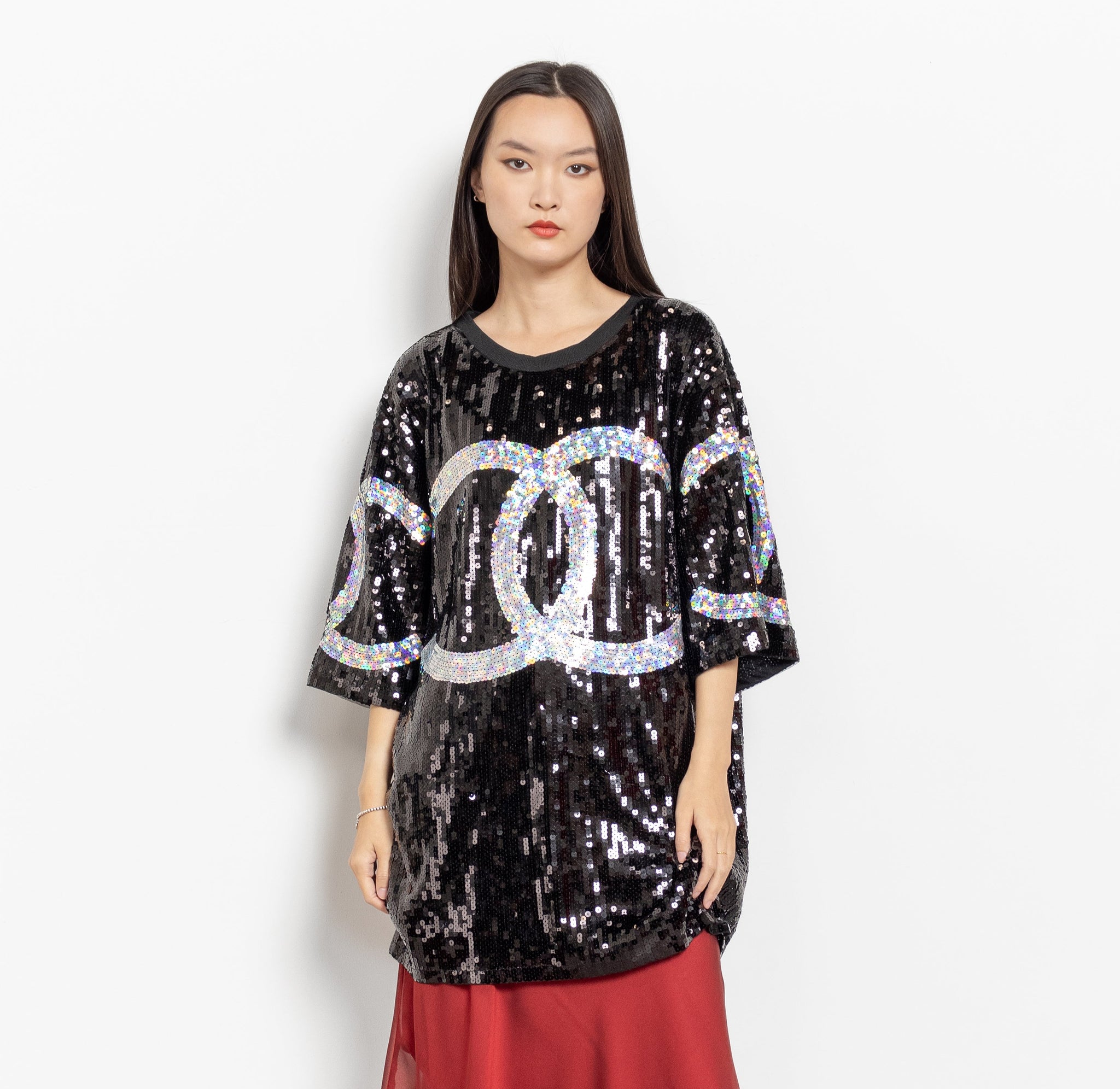 Woman wearing a black sequin top with a red skirt and silver boots on a white background