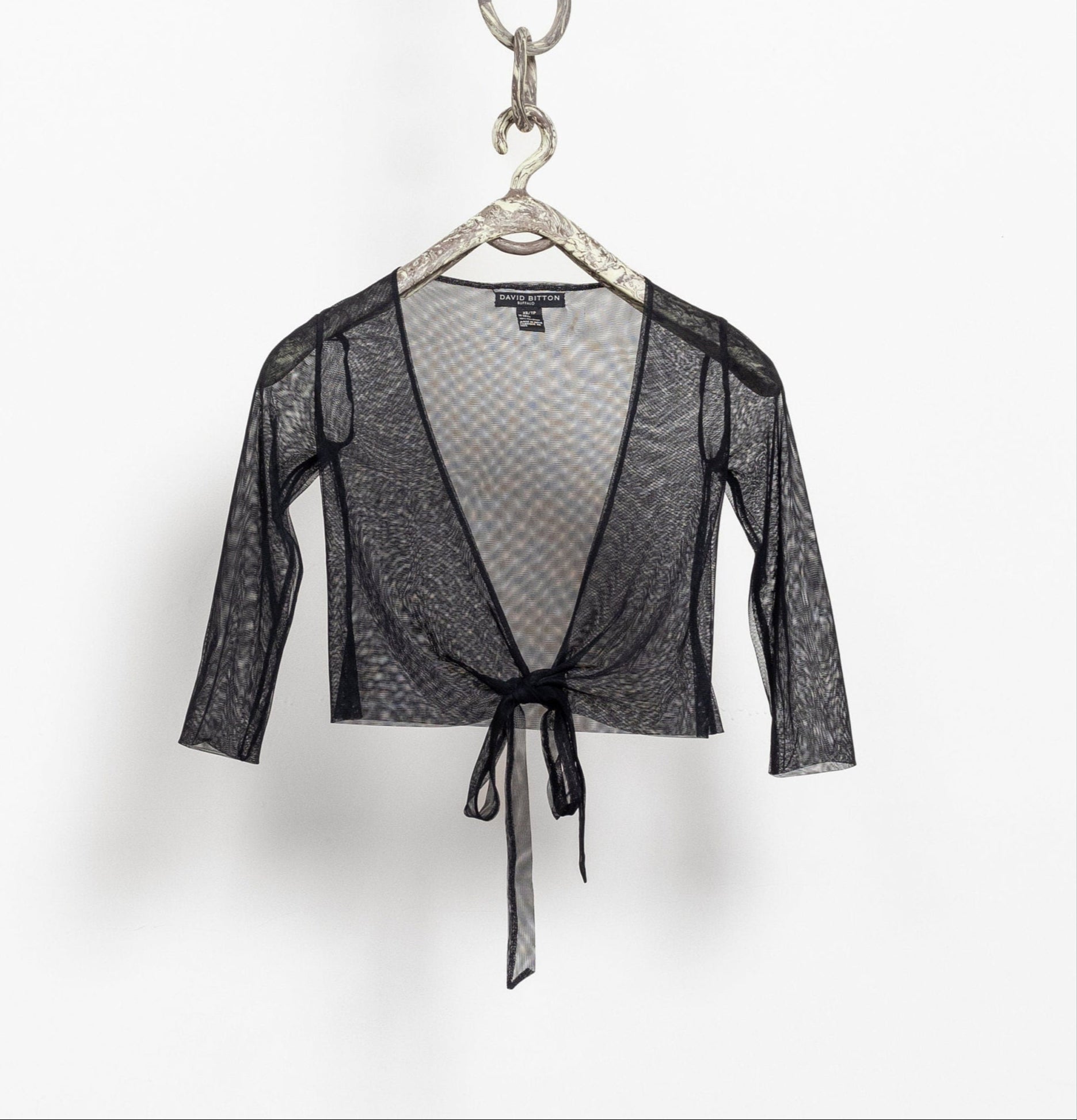 Black lace top on a hanger against a white background