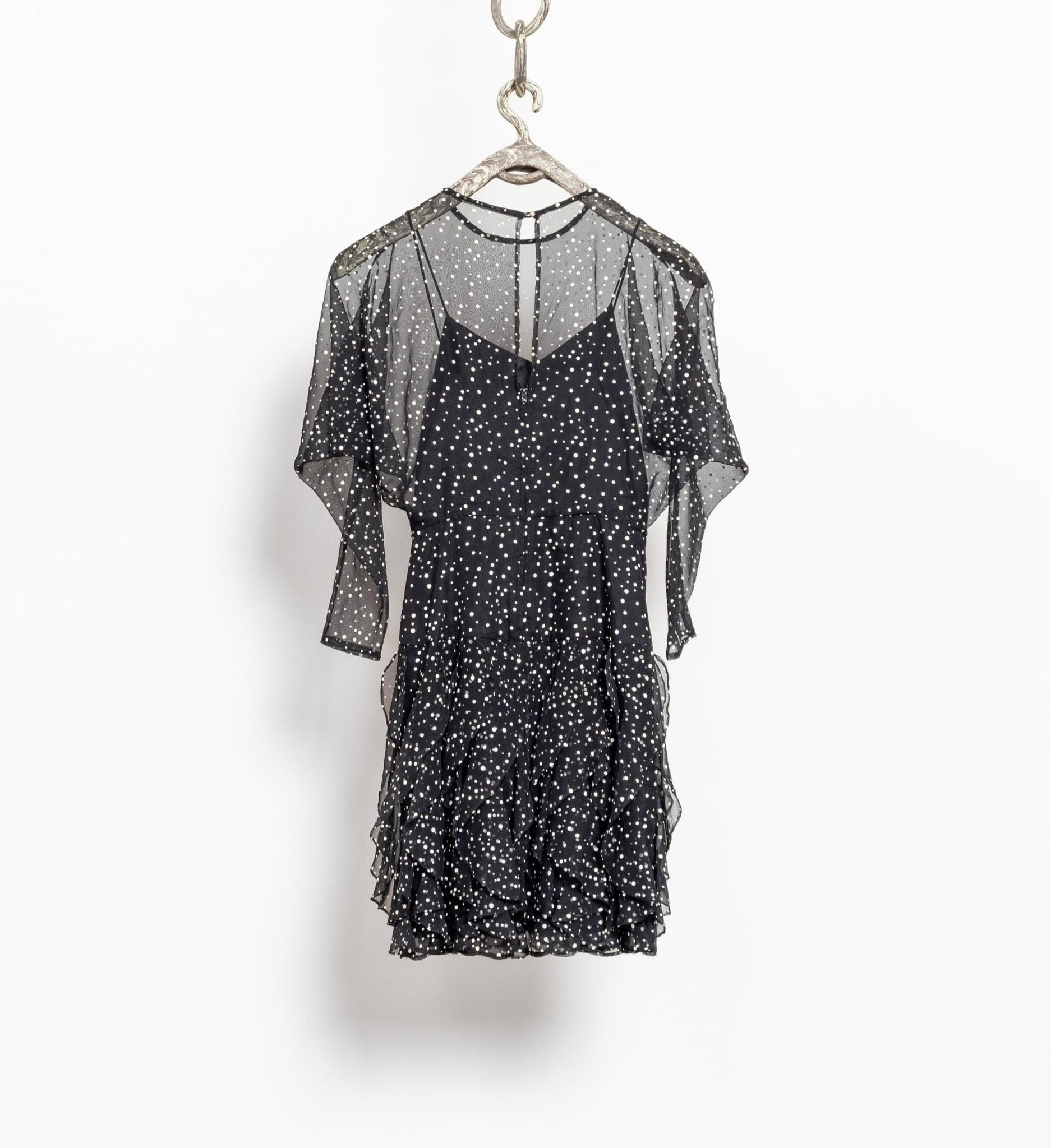 Black dress with sheer sleeves on a hanger against a white background