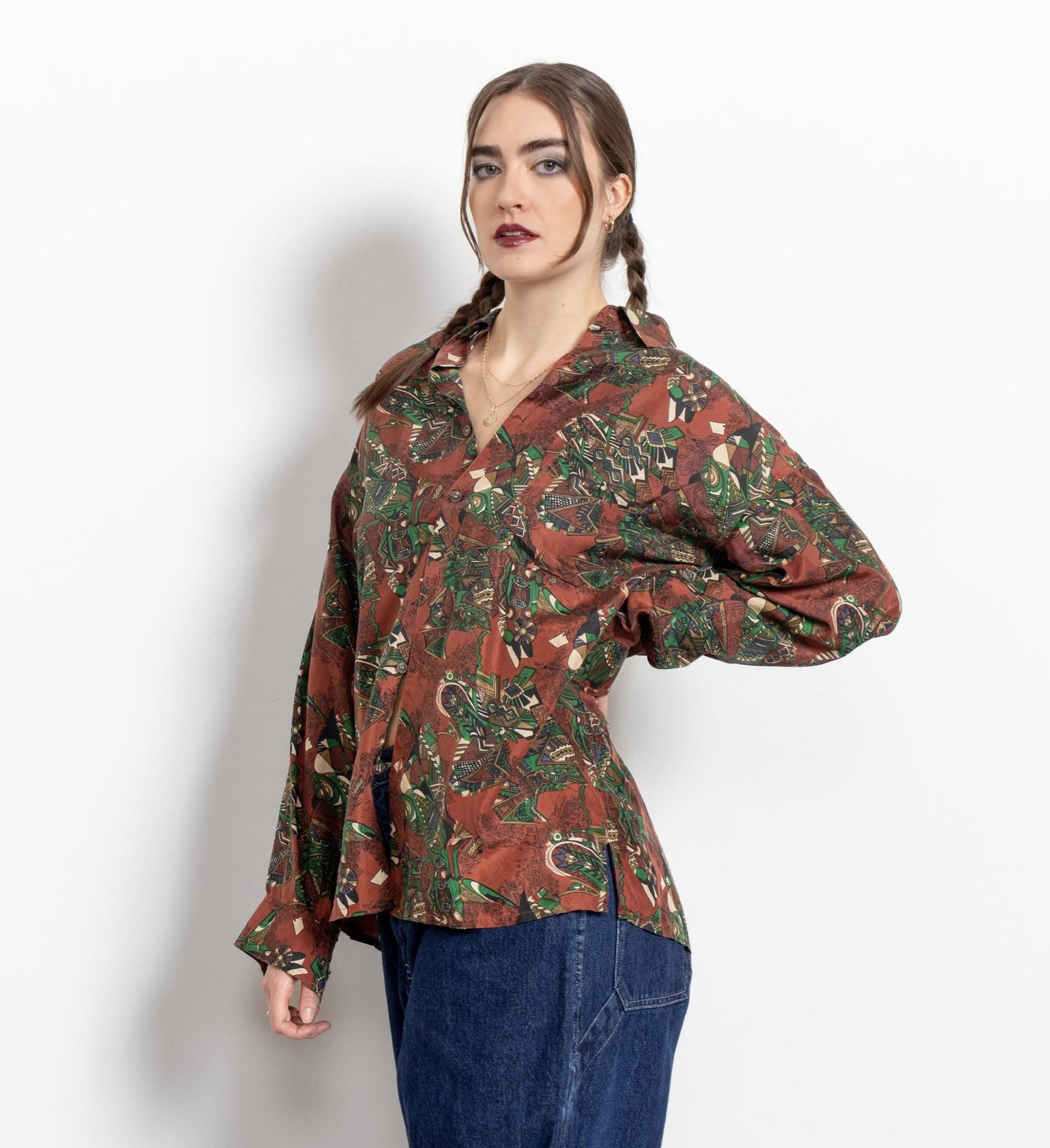 Woman wearing a patterned shirt and jeans on a white background