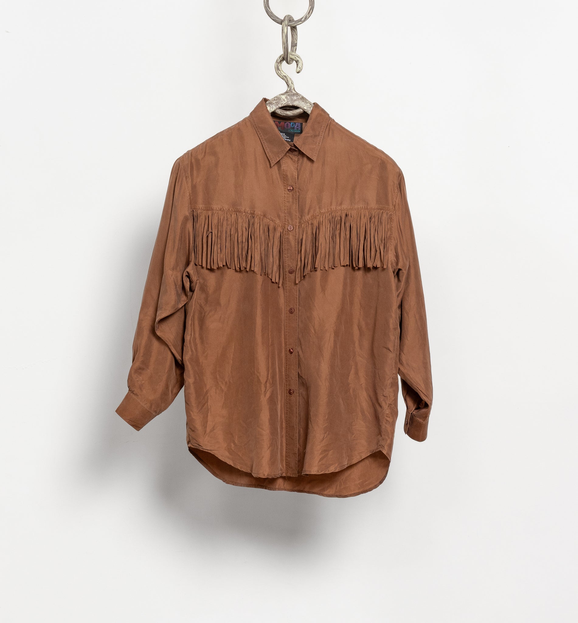 Brown fringed shirt on a hanger against a white background