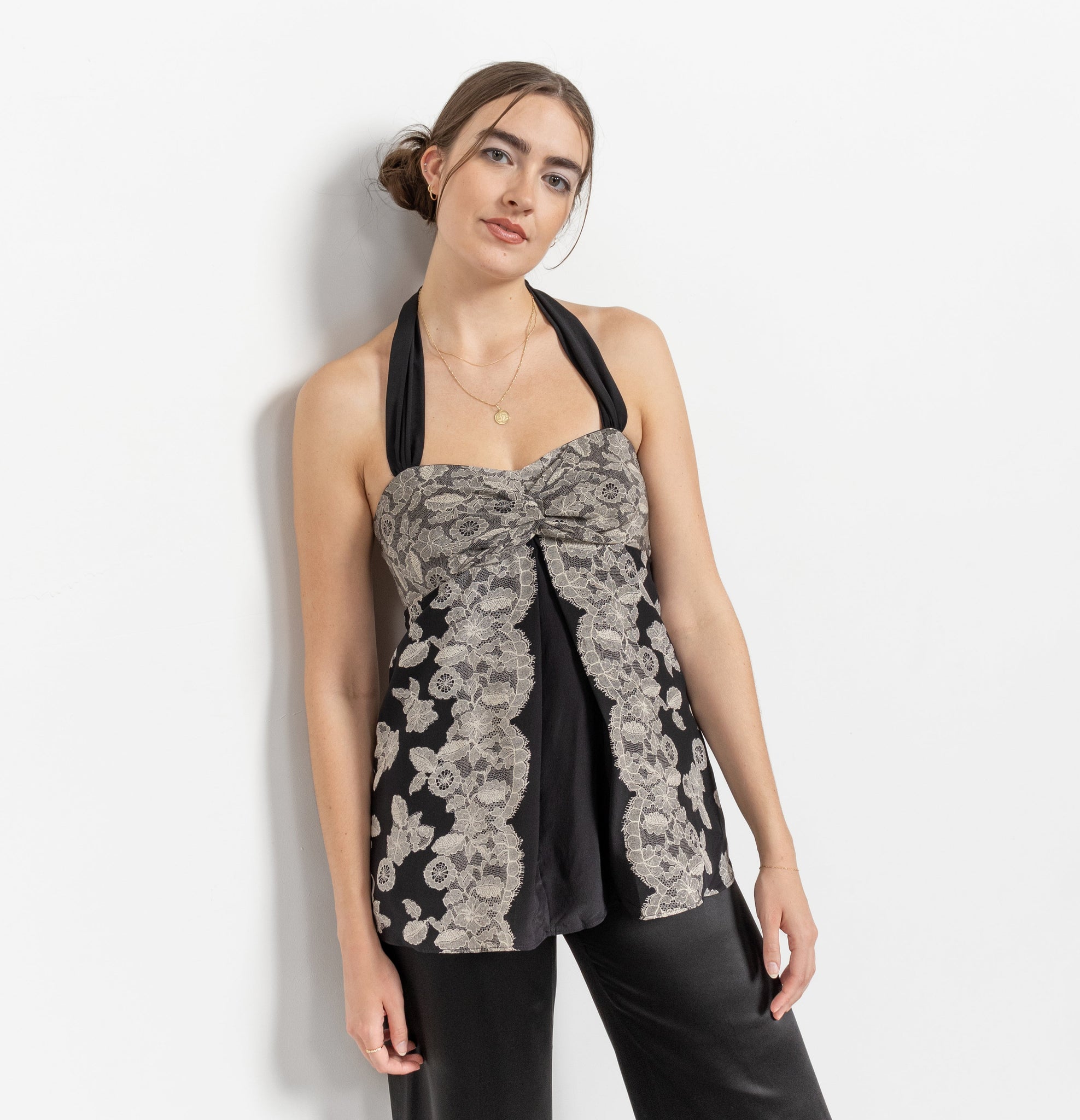 Woman wearing a black sleeveless top with floral lace details on a white background