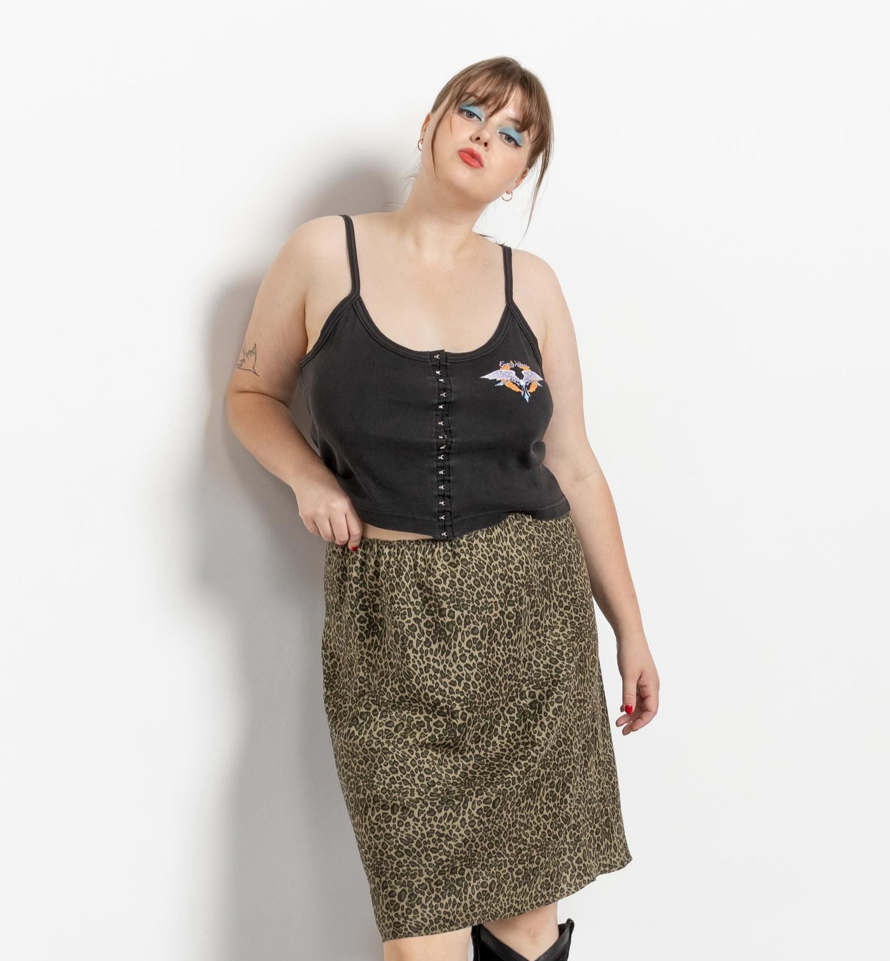 Woman wearing a black top and patterned skirt with knee-high boots on a white background