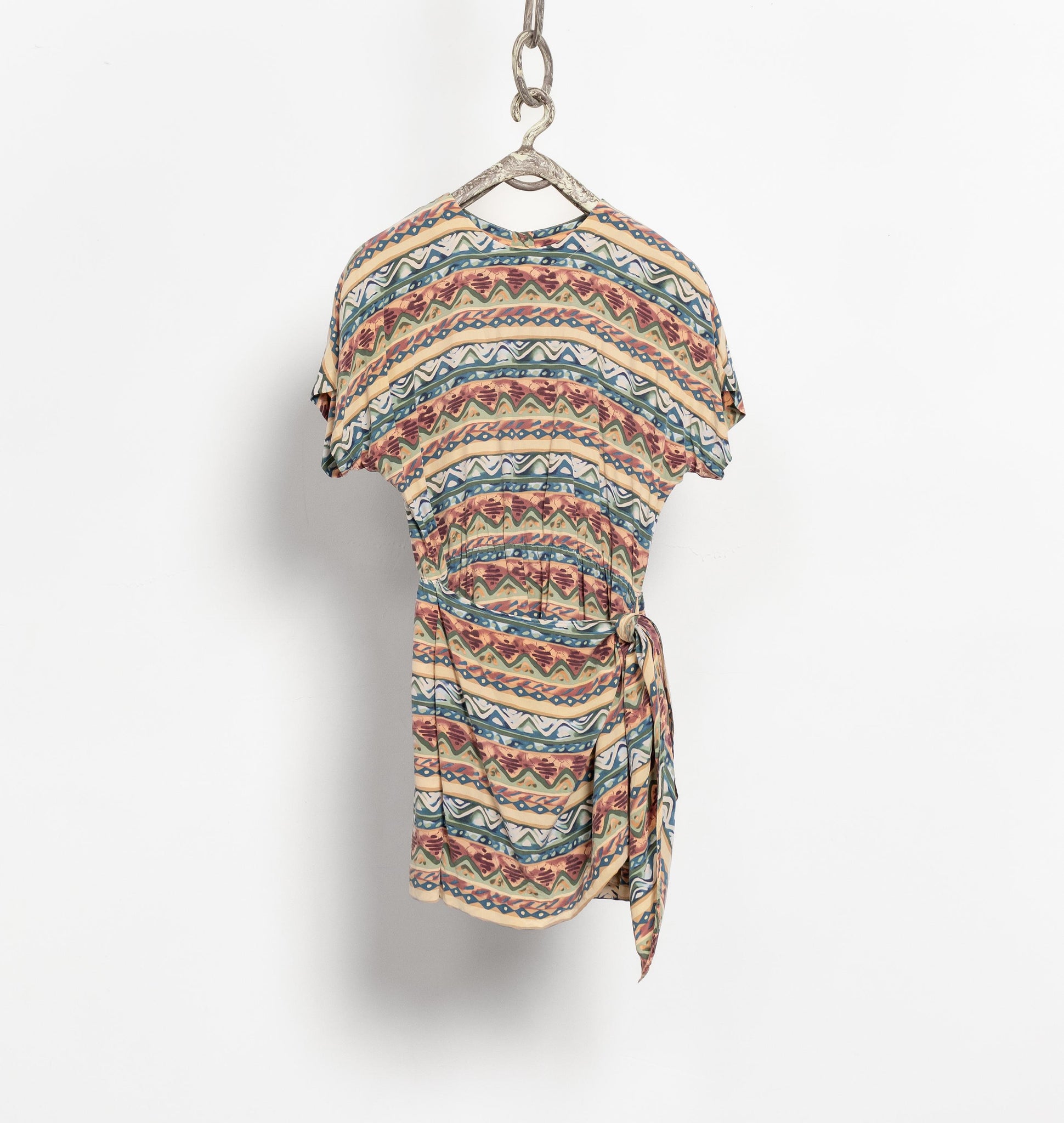 Multicolored patterned dress on a hanger against a white background