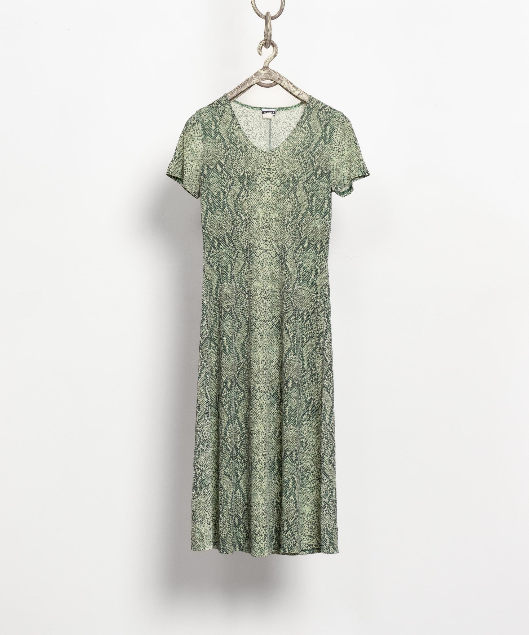 Green patterned dress on a hanger against a white background