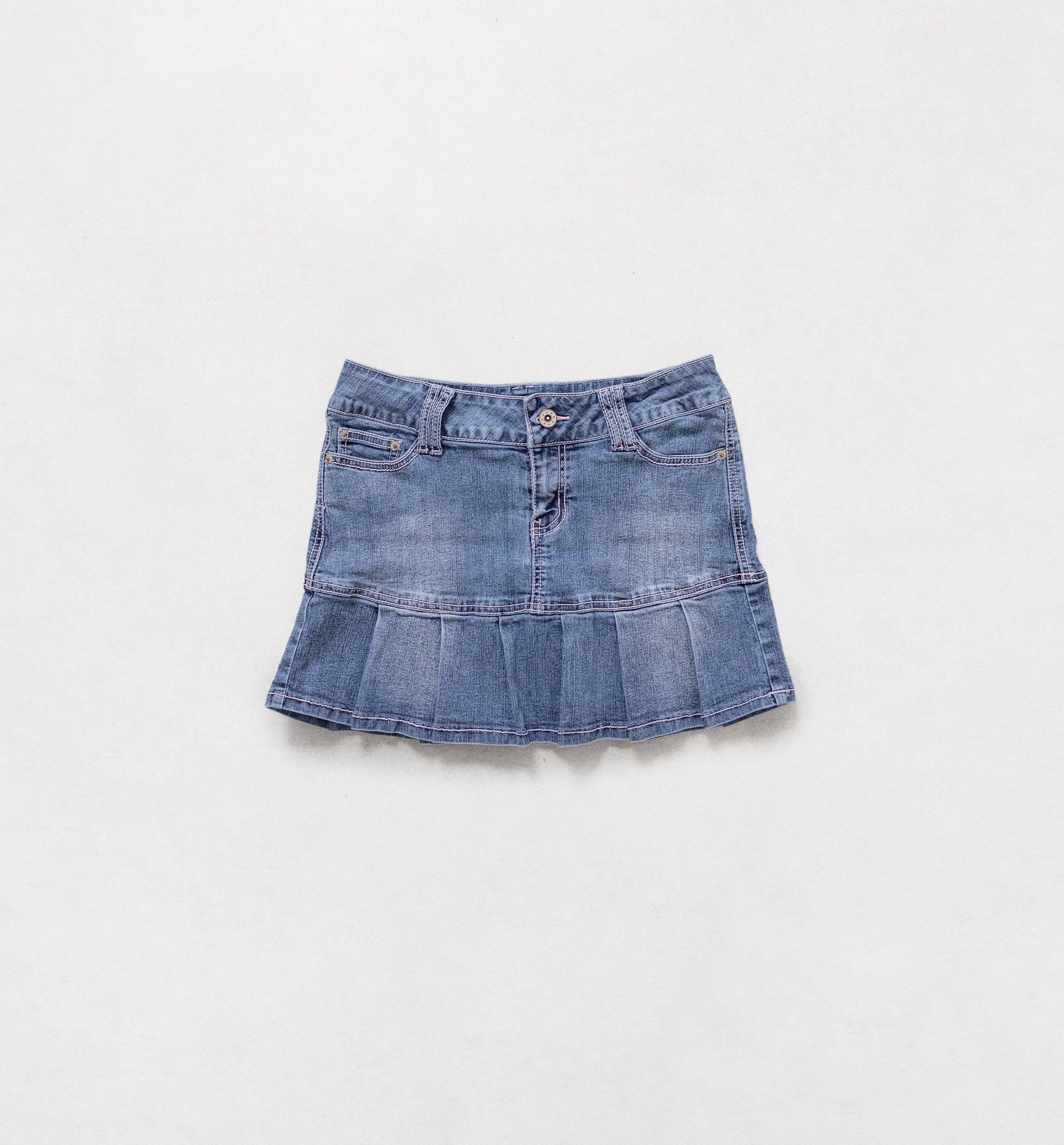 A vintage 2000's low rise stretch denim mini skirt with pleats and contrasting pink stitching, featuring a button and zipper fly, displayed on a plain background.