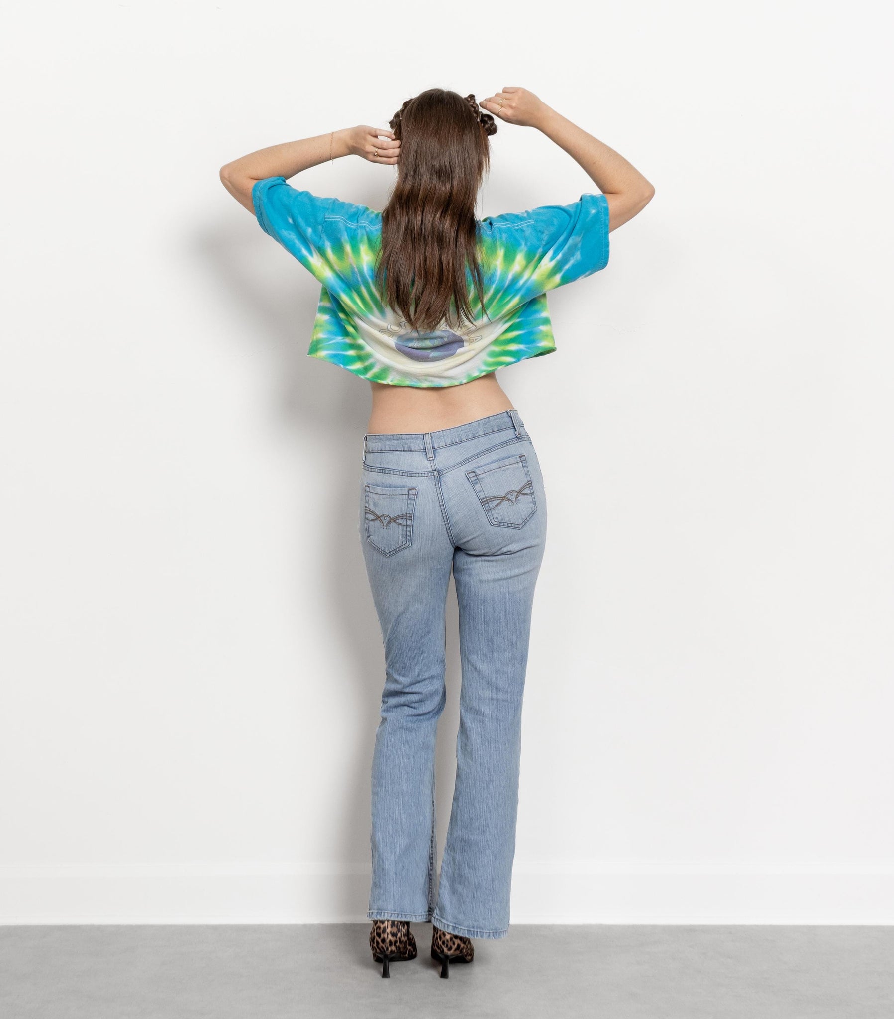 Person wearing a tie-dye shirt and jeans against a white background