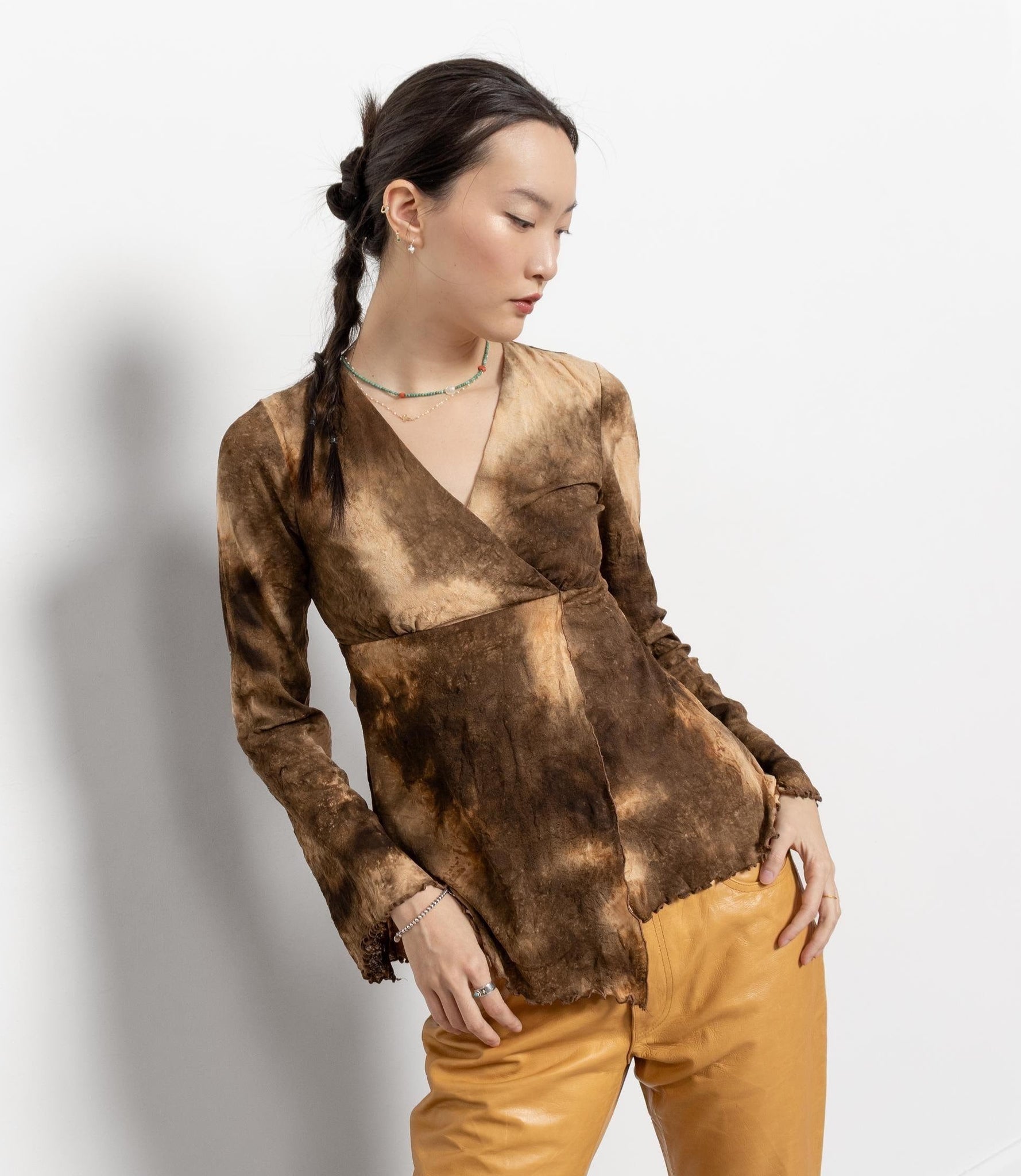 Woman wearing a brown tie-dye top and yellow pants on a white background