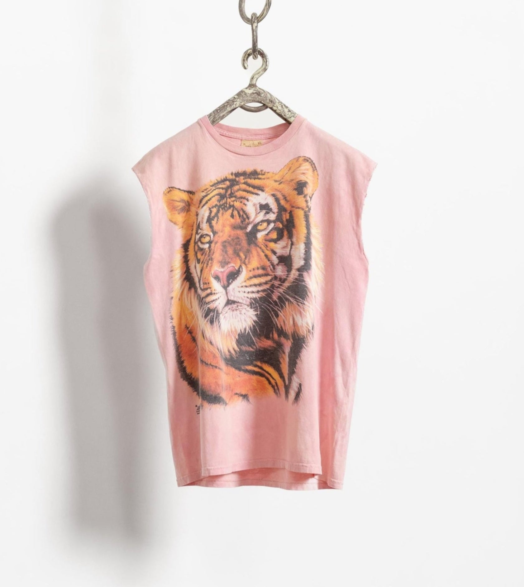 A pink sleeveless tiger tee shirt with a graphic print of a tiger's face, displayed on a hanger against a white background.