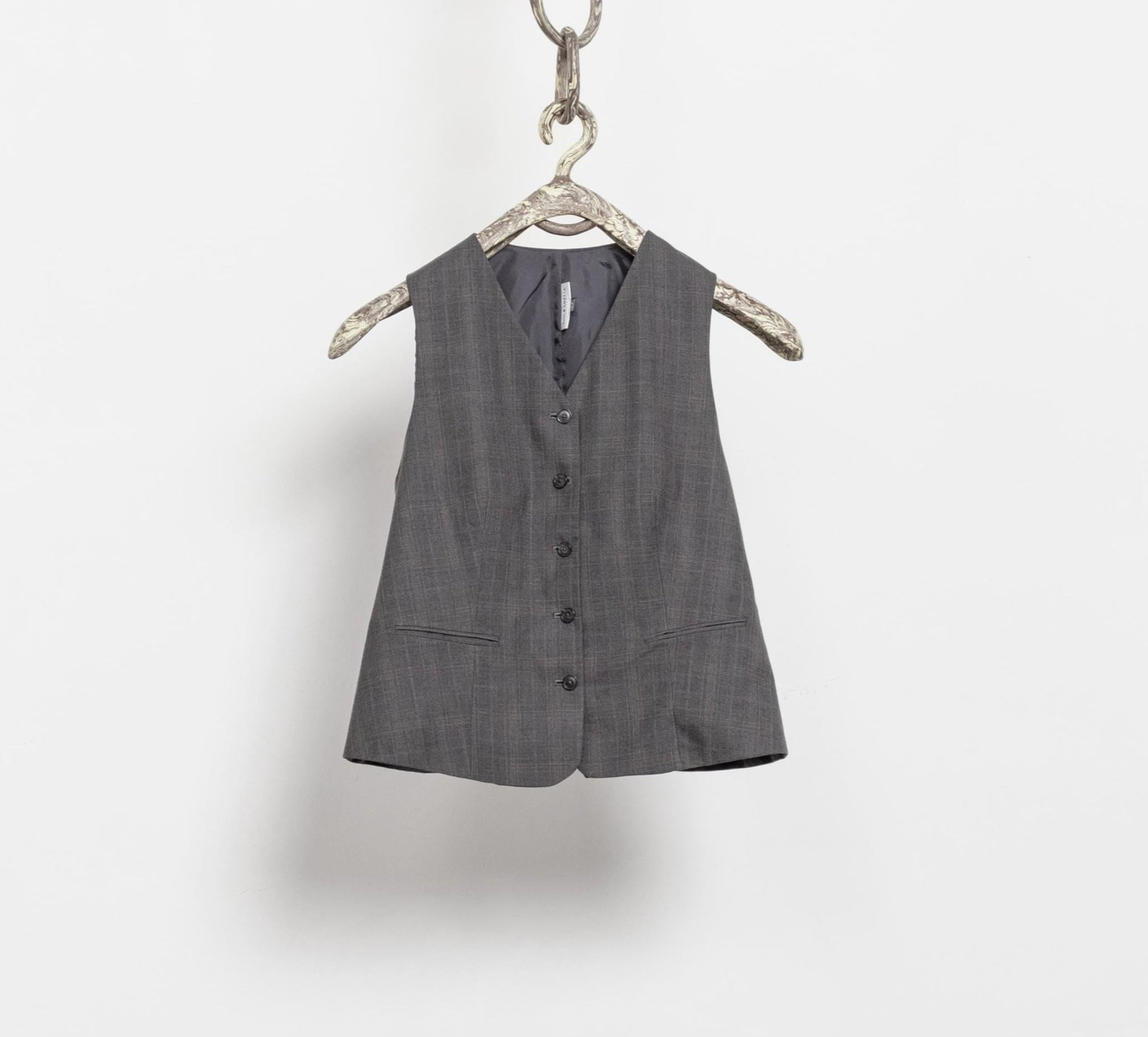 Gray vest hanging on a hanger against a white background